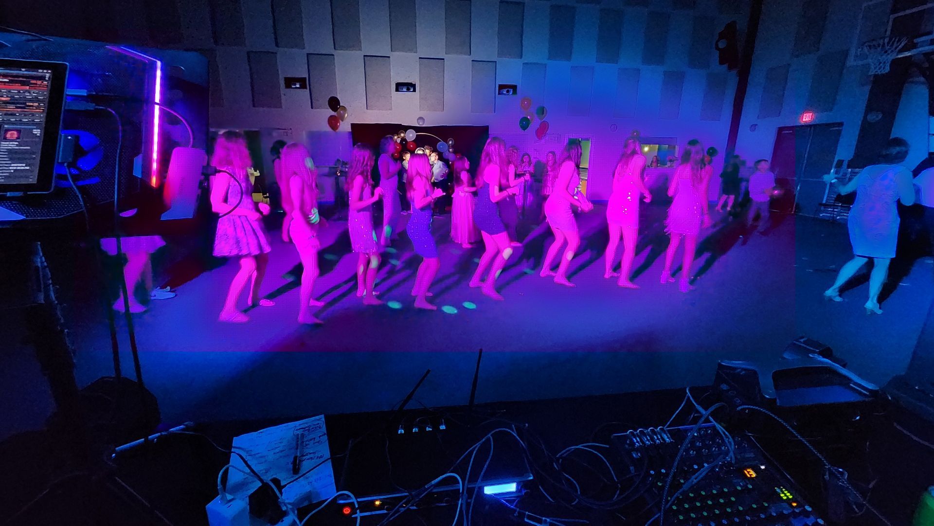 A group of people are dancing in a dark room with glow in the dark lights.