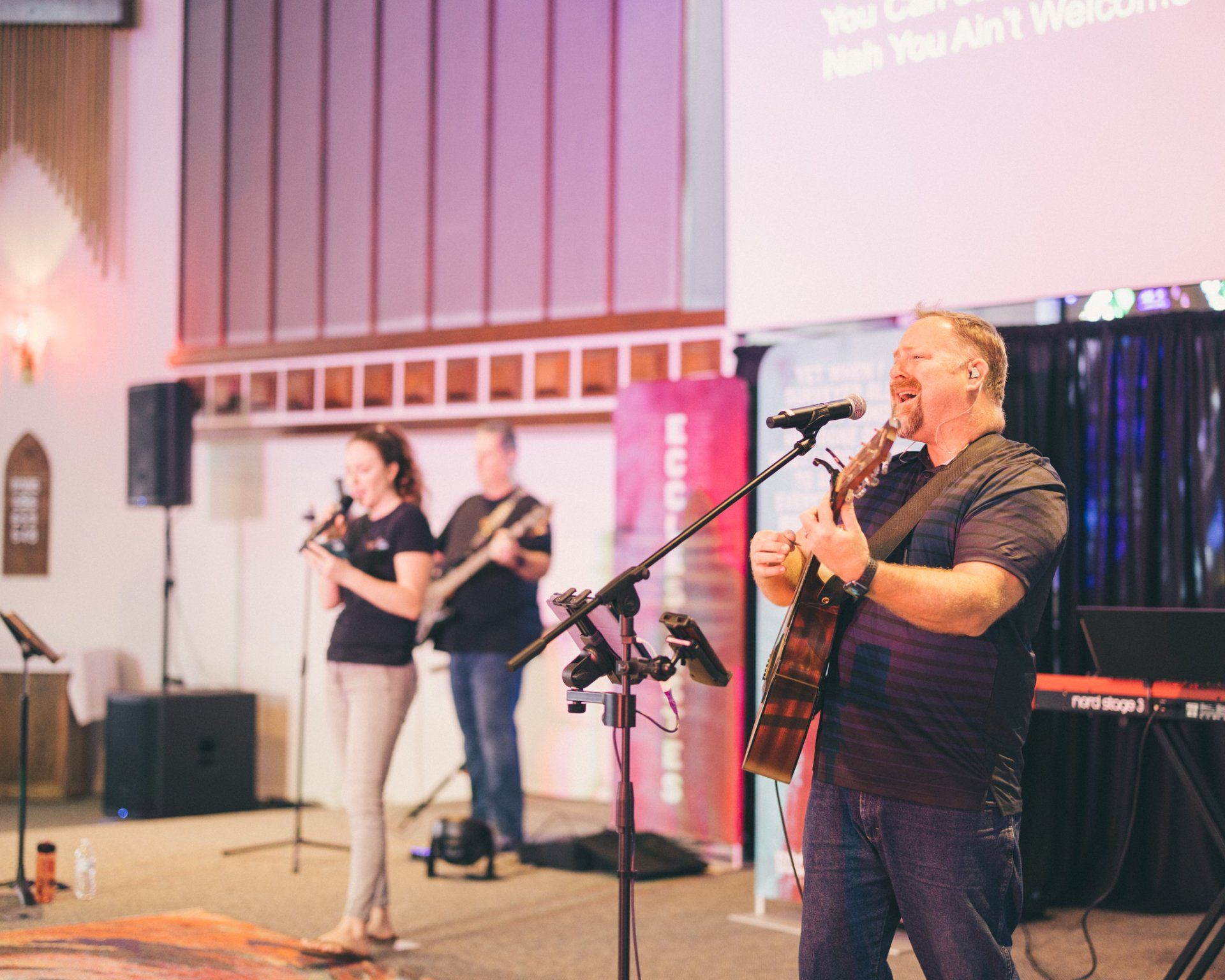 A man is singing into a microphone while playing a guitar.