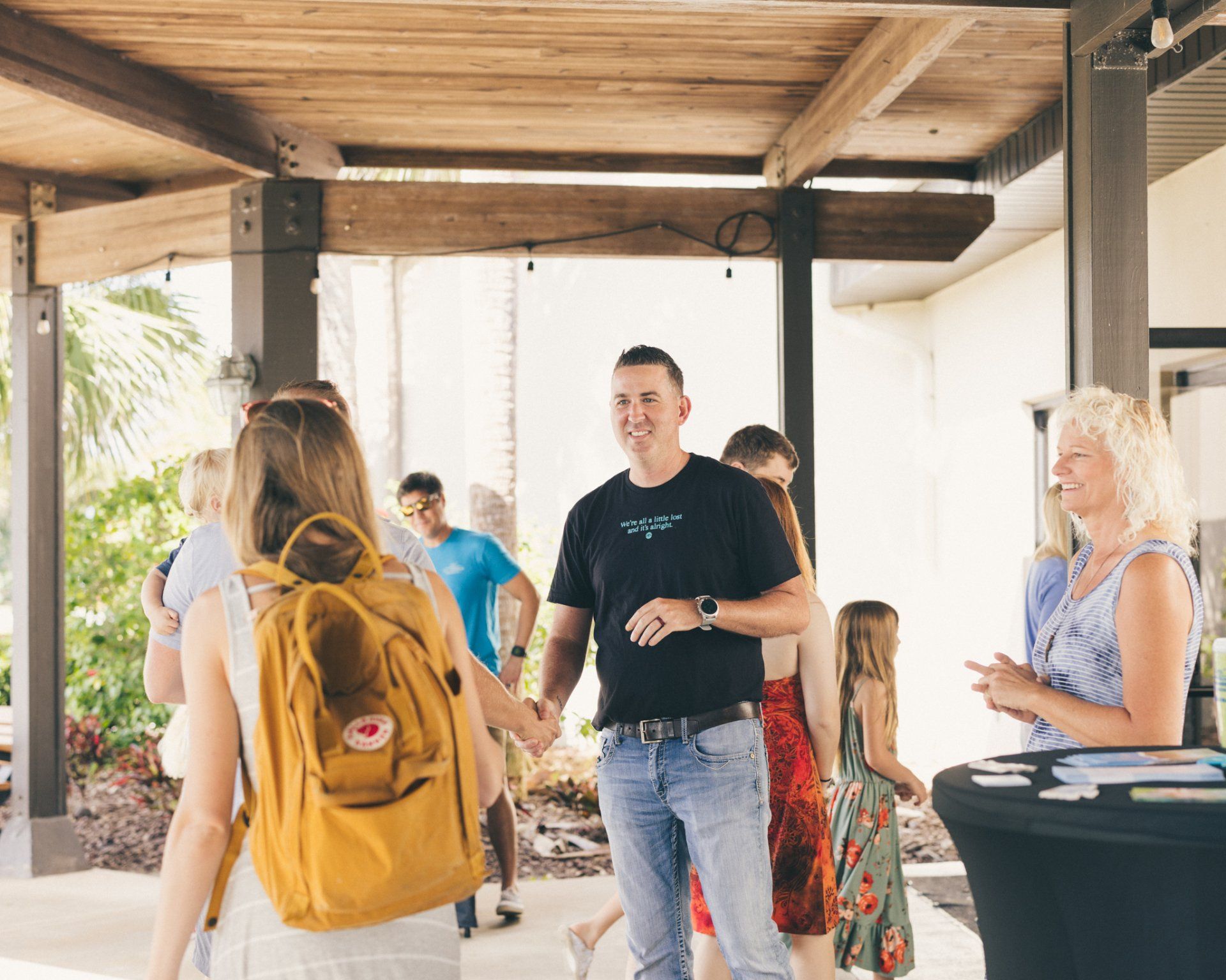 A group of people are standing under a canopy talking to each other.
