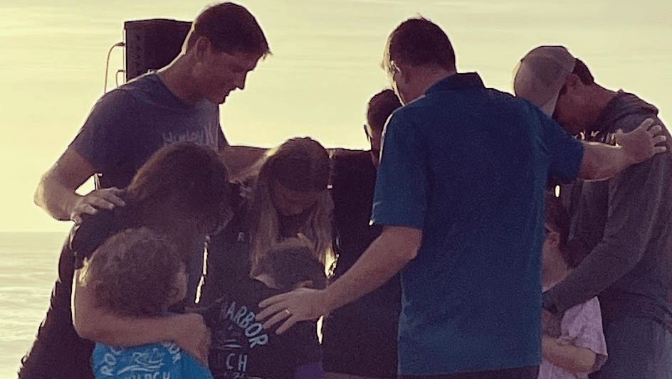 A group of people are standing in a circle with their arms around each other.