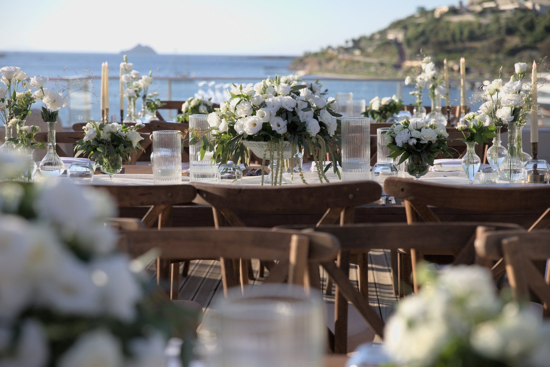 A long table with flowers on it and a view of the ocean. elementa
