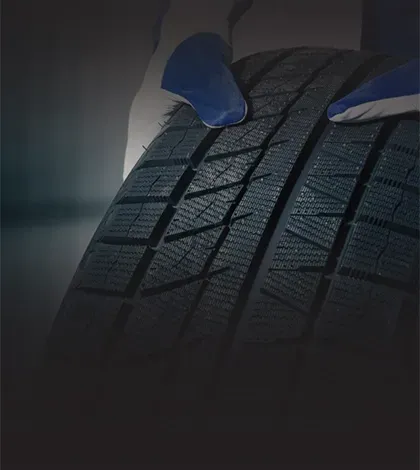 Up close to technician wearing gloves holding rim of tire | Power Tire