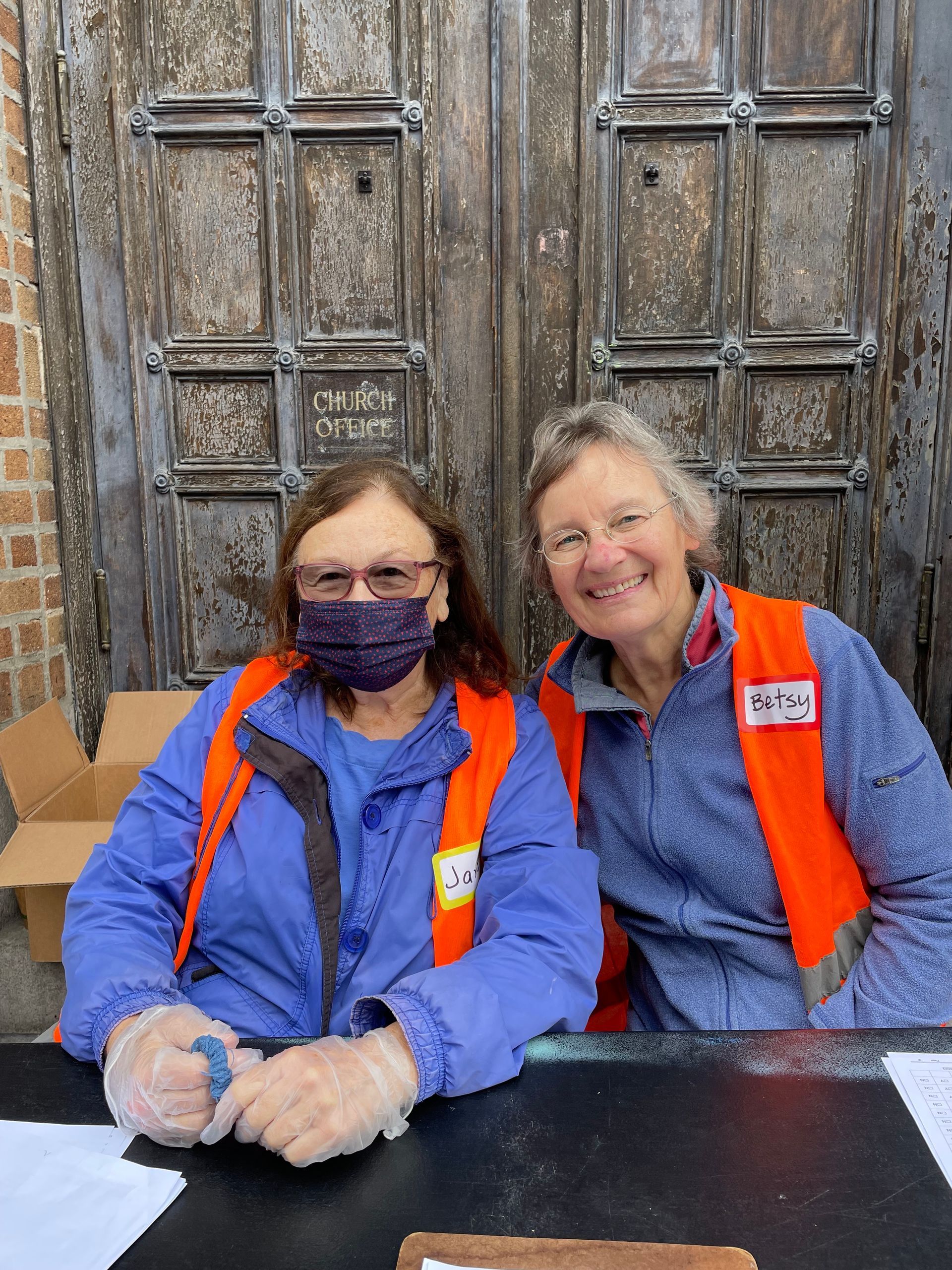 Two adult volunteers in orange safety vests for one of our volunteer service opportunities