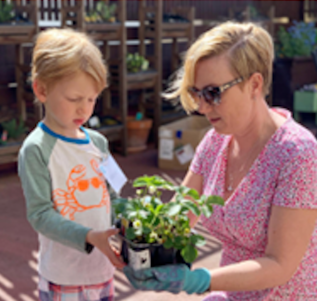 A mom and son holding a plant together, gardening