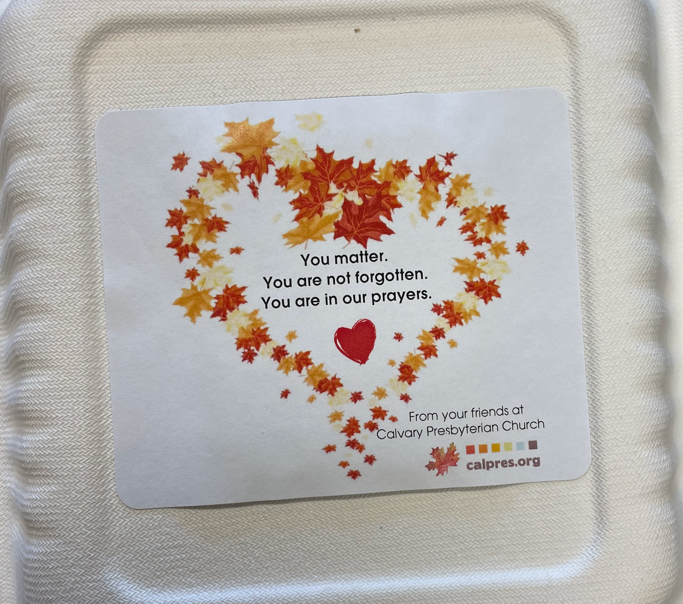 The top of a to-go container full of food that says