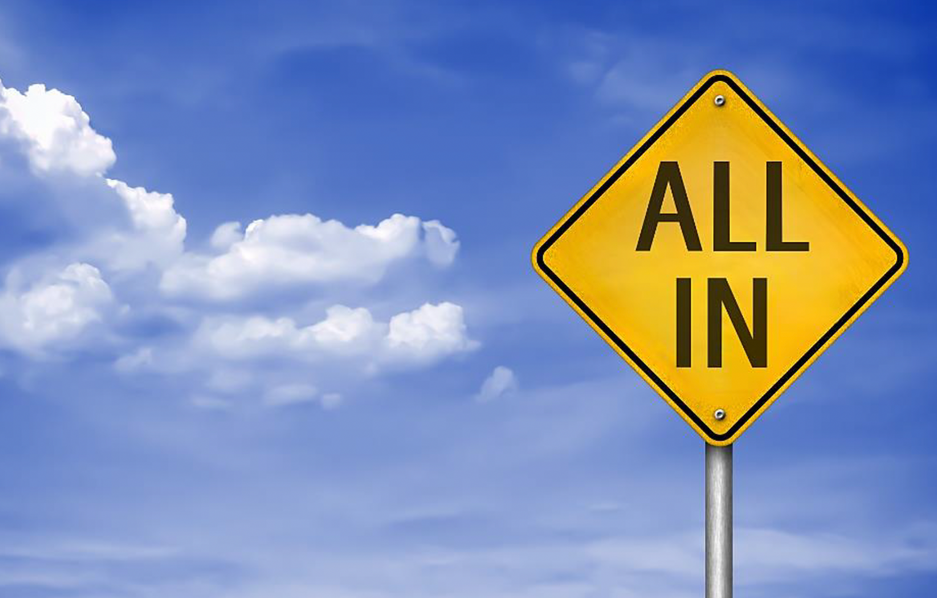 A yellow diamond road sign against a blue sky background, the sign reads 