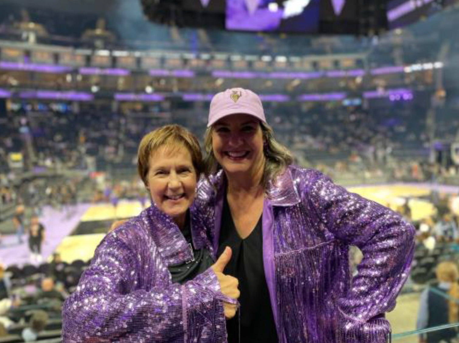 Marci and Jen at a SF Valkyries game, both are wearing sequin purple jackets and smiling