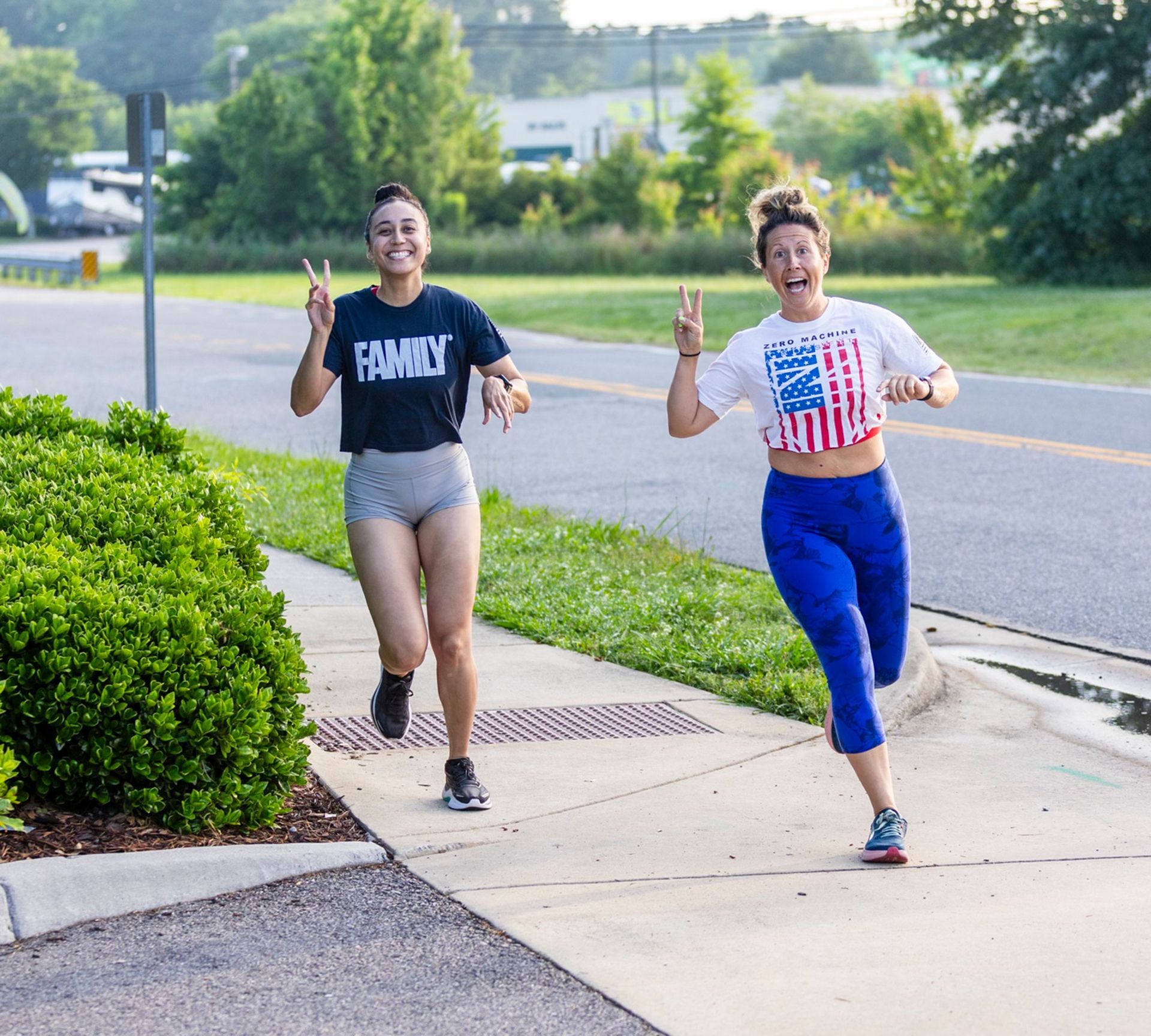 Two women running down a sidewalk one wearing a shirt that says family