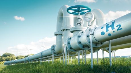 Eine Reihe von Wasserstoffleitungen, die durch ein Grasfeld führen - Verein zur Dekarbonisierung der Industrie