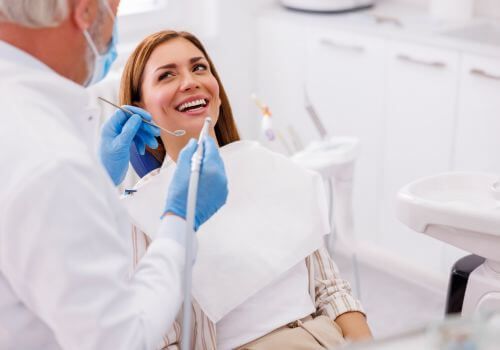 Dentist examining a smiling patient in a bright dental clinic