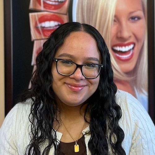 Portrait of a smiling person with glasses in front of dental posters