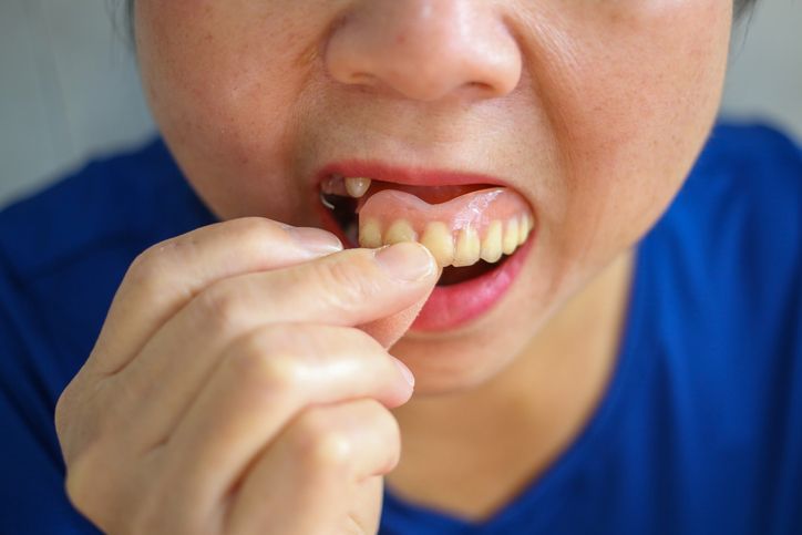 Person flossing teeth close-up, wearing a blue shirt