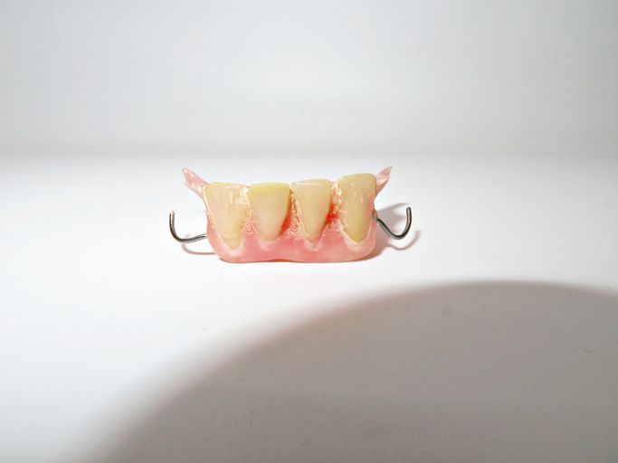 Artificial denture with pink gums and metal clasps on a white background