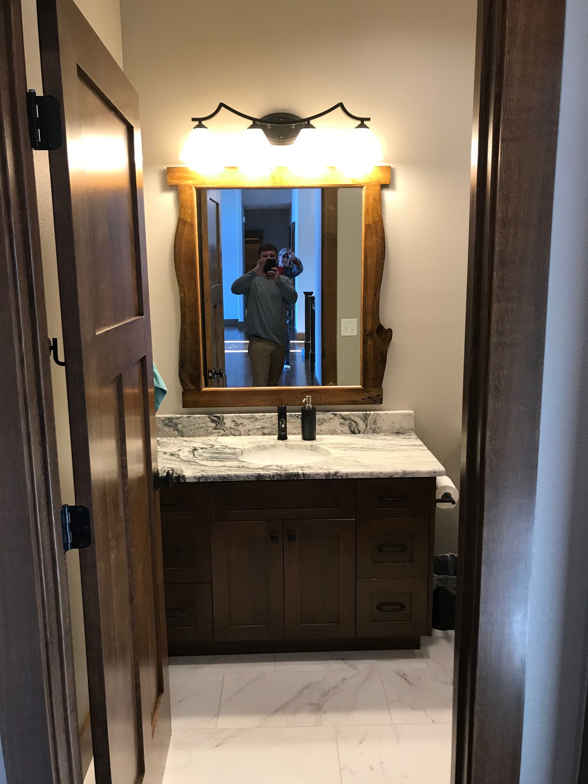 A bathroom with a sink and a mirror with a wooden frame