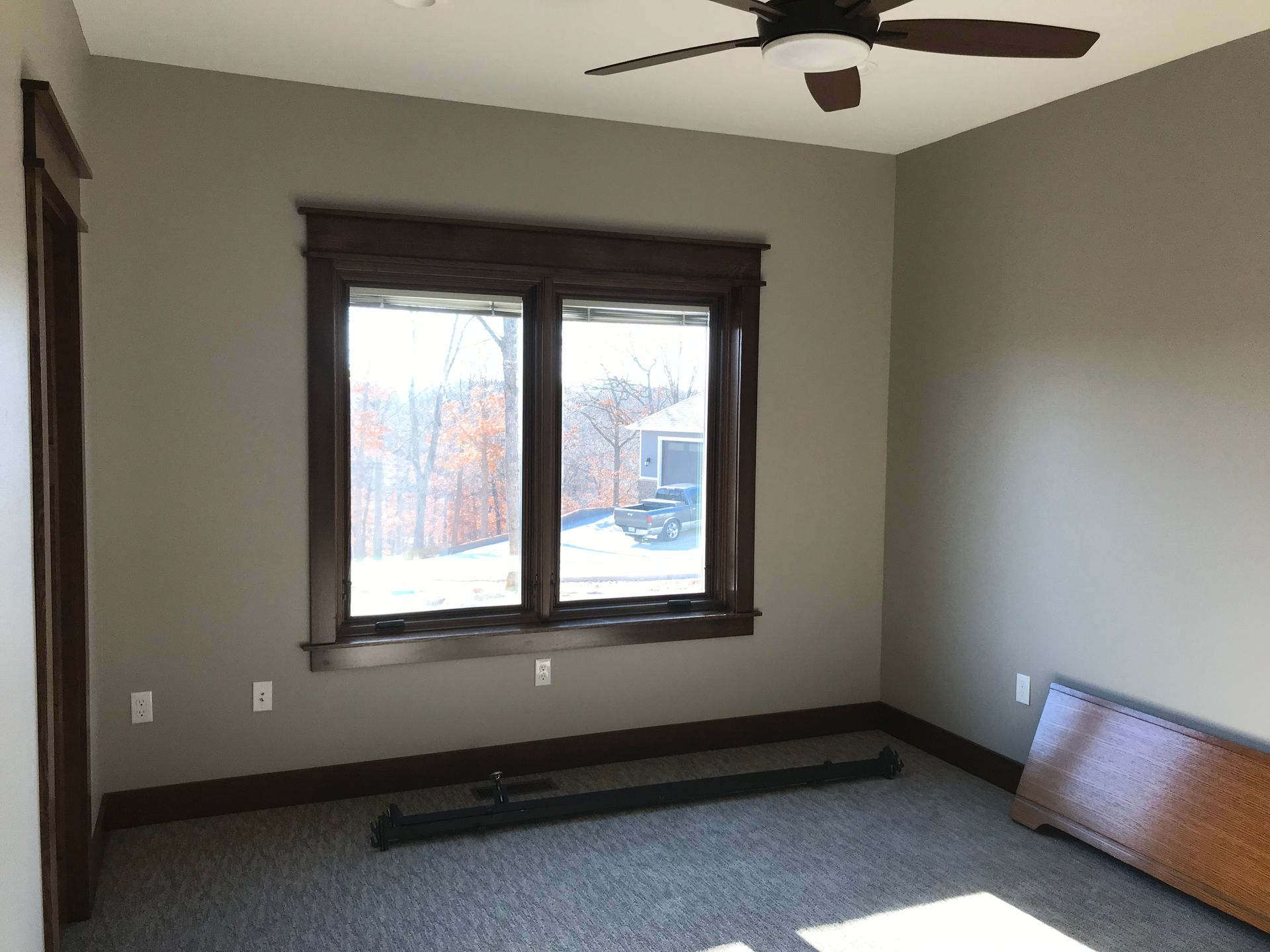 An empty room with two windows and a ceiling fan