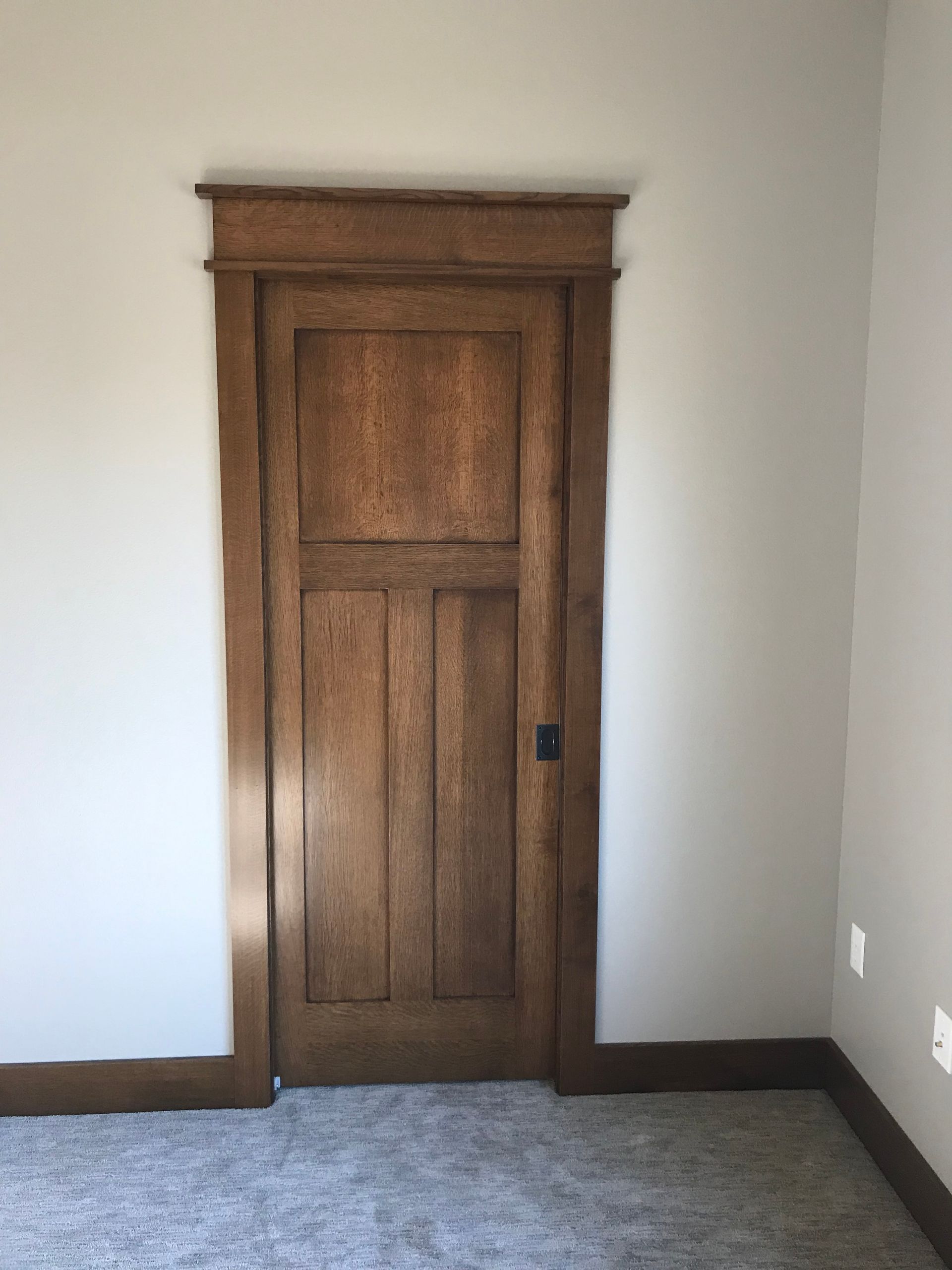 An empty room with a wooden door and white walls