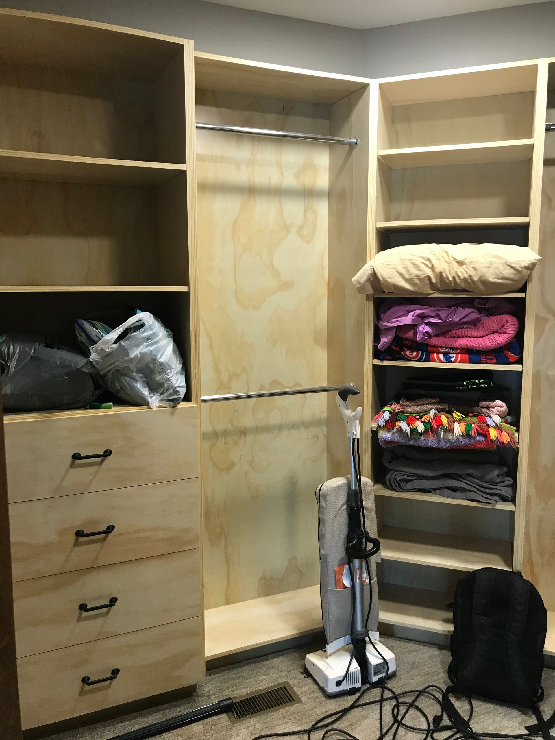 A closet with a vacuum cleaner in the middle of it.