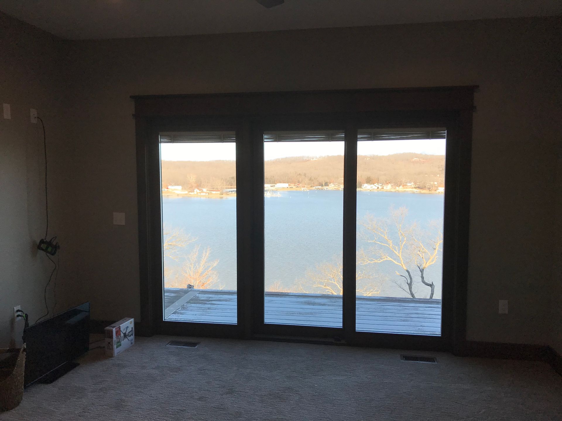 An empty room with a view of a lake through sliding glass doors