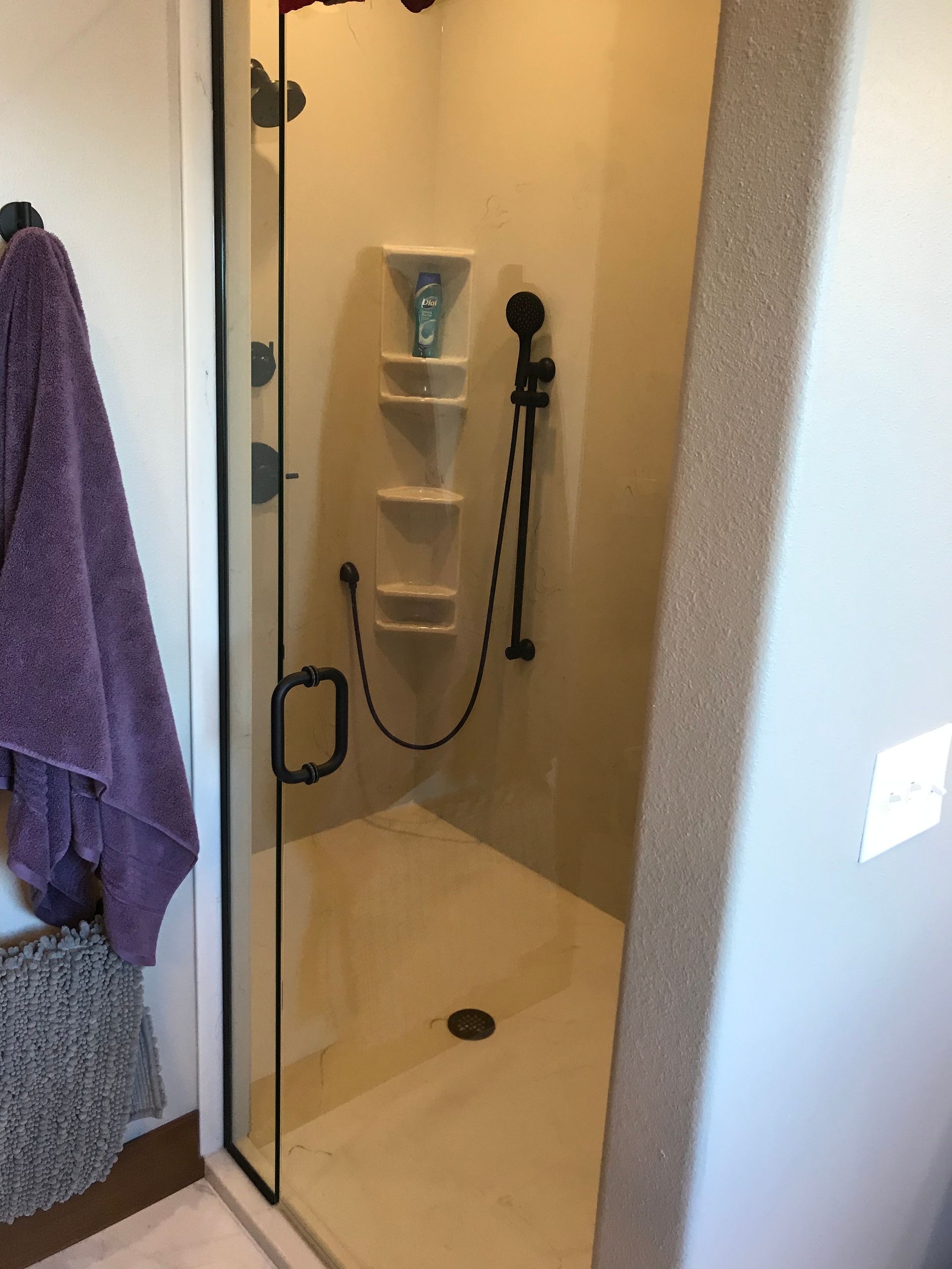 A shower with a purple towel hanging on the wall
