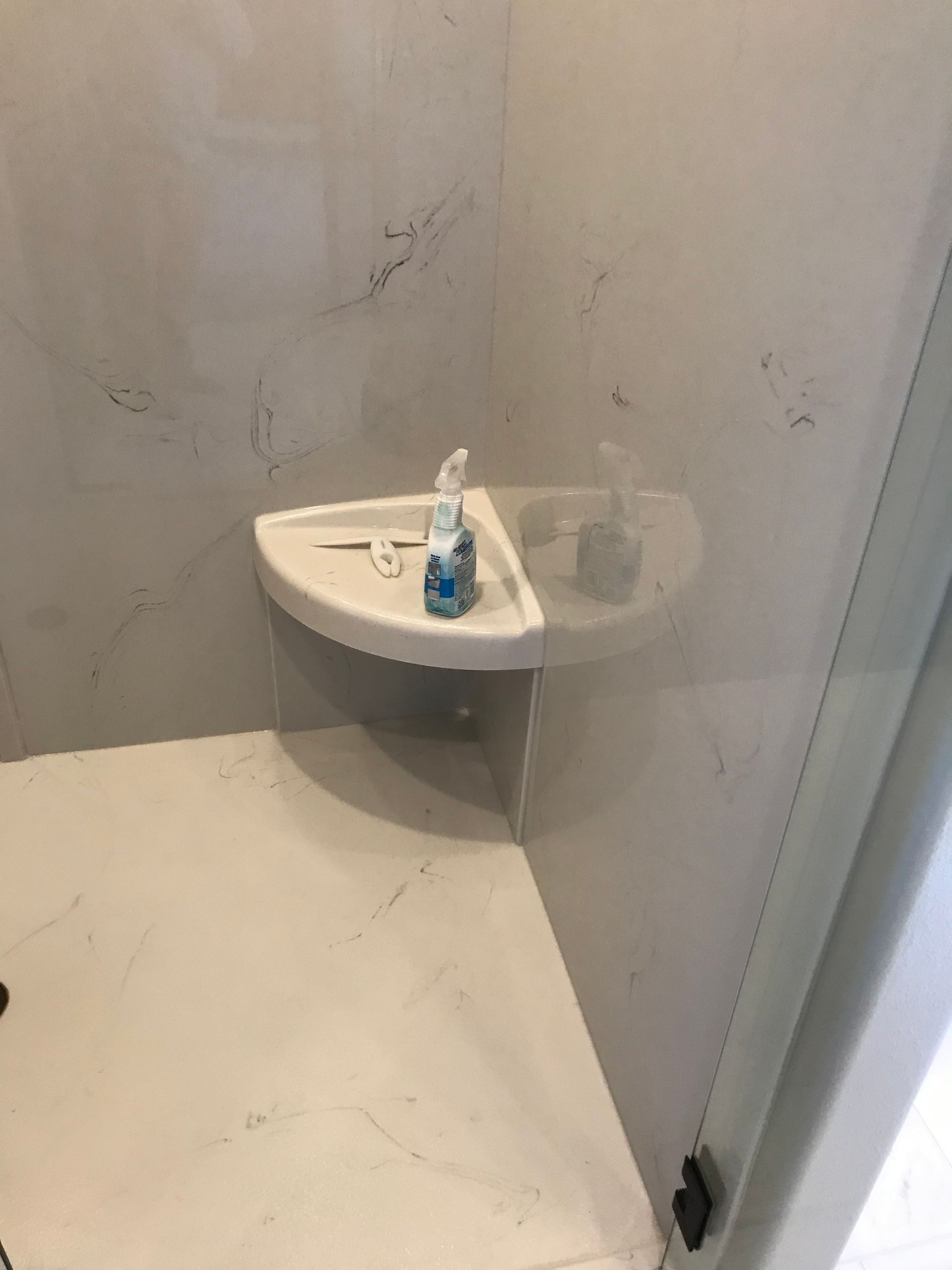 A bathroom with a corner sink and a soap dispenser on it.