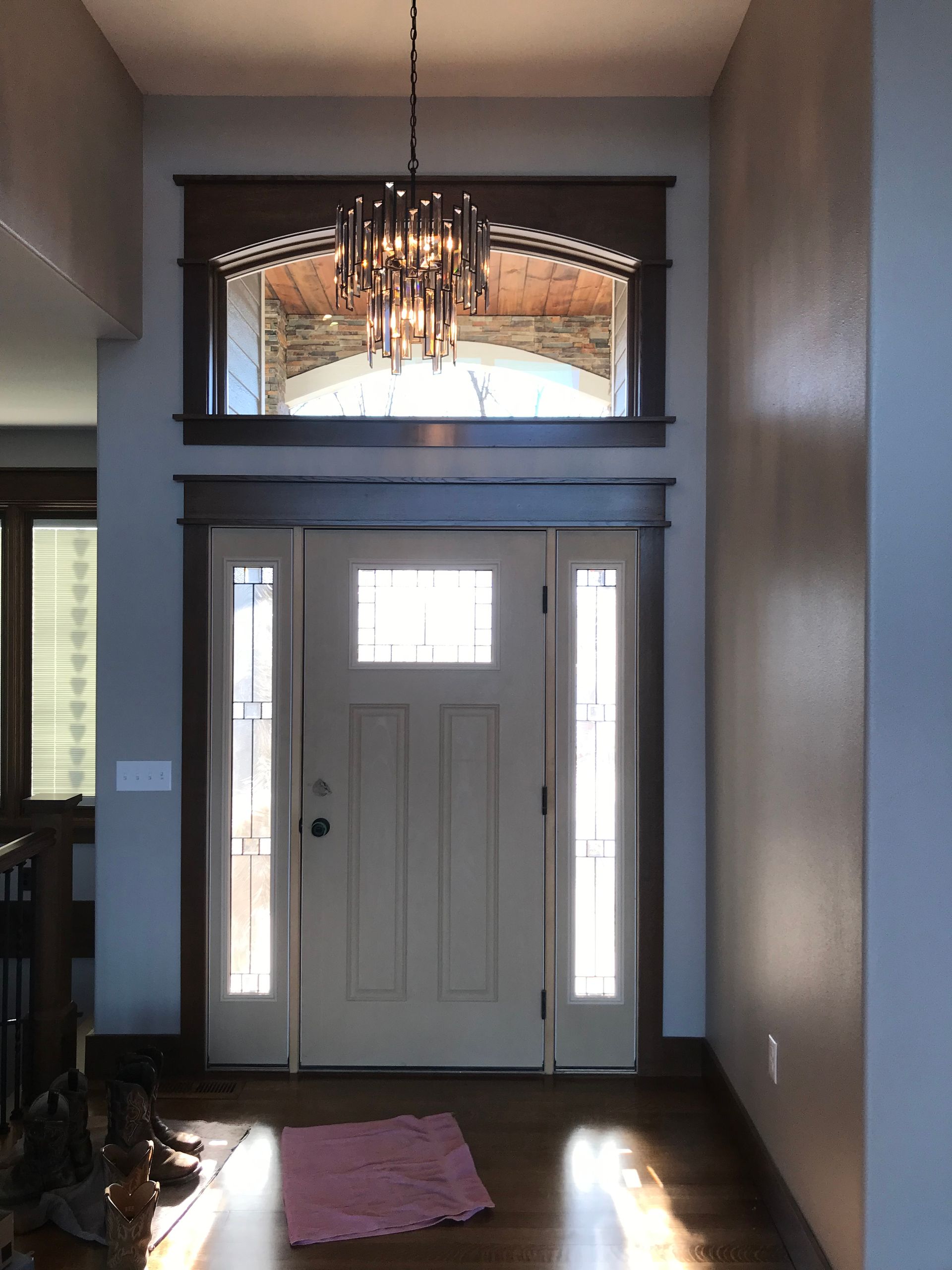 A hallway with a white door and a chandelier hanging from the ceiling