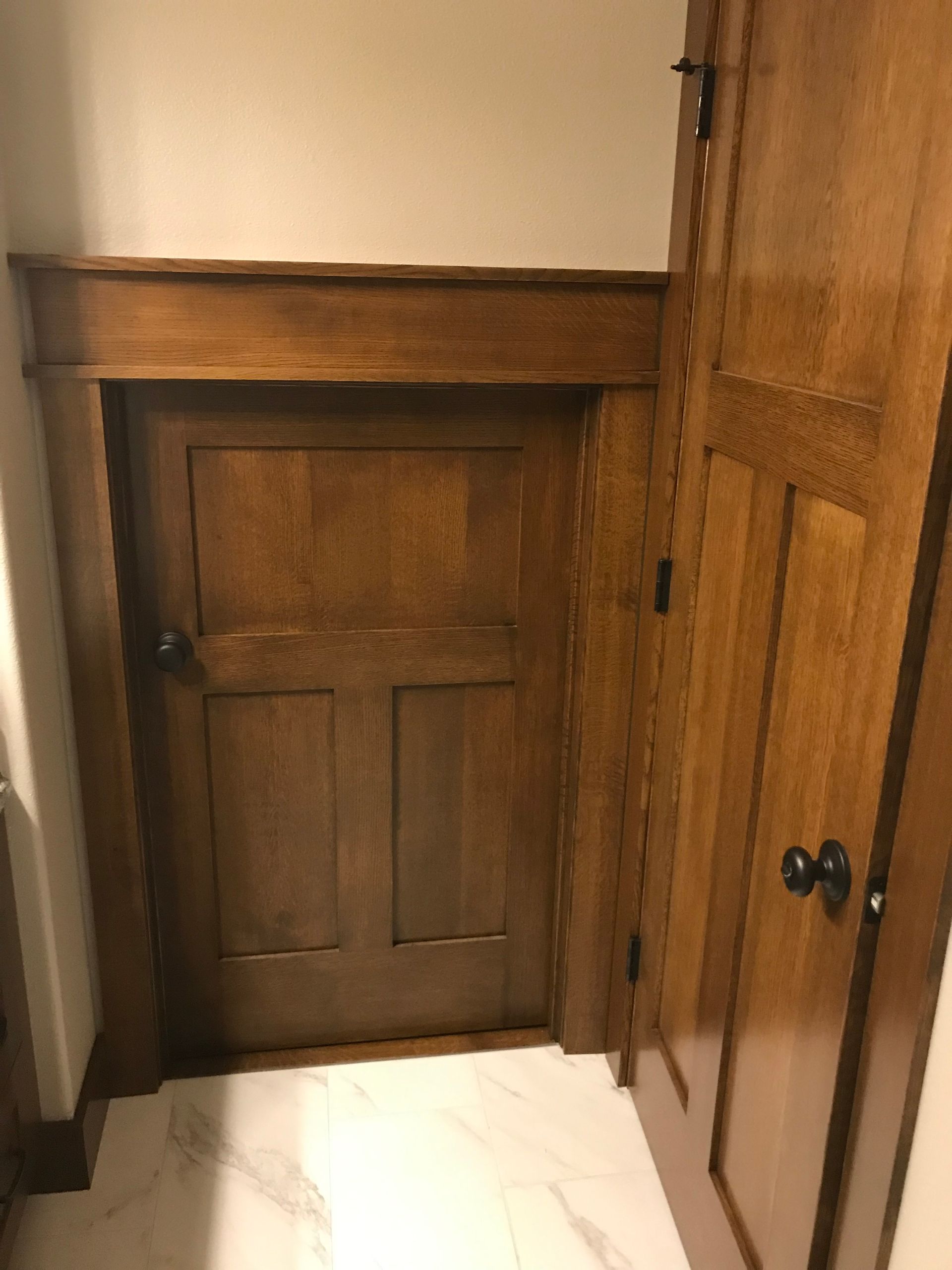A wooden door is open in a room with a white tile floor.