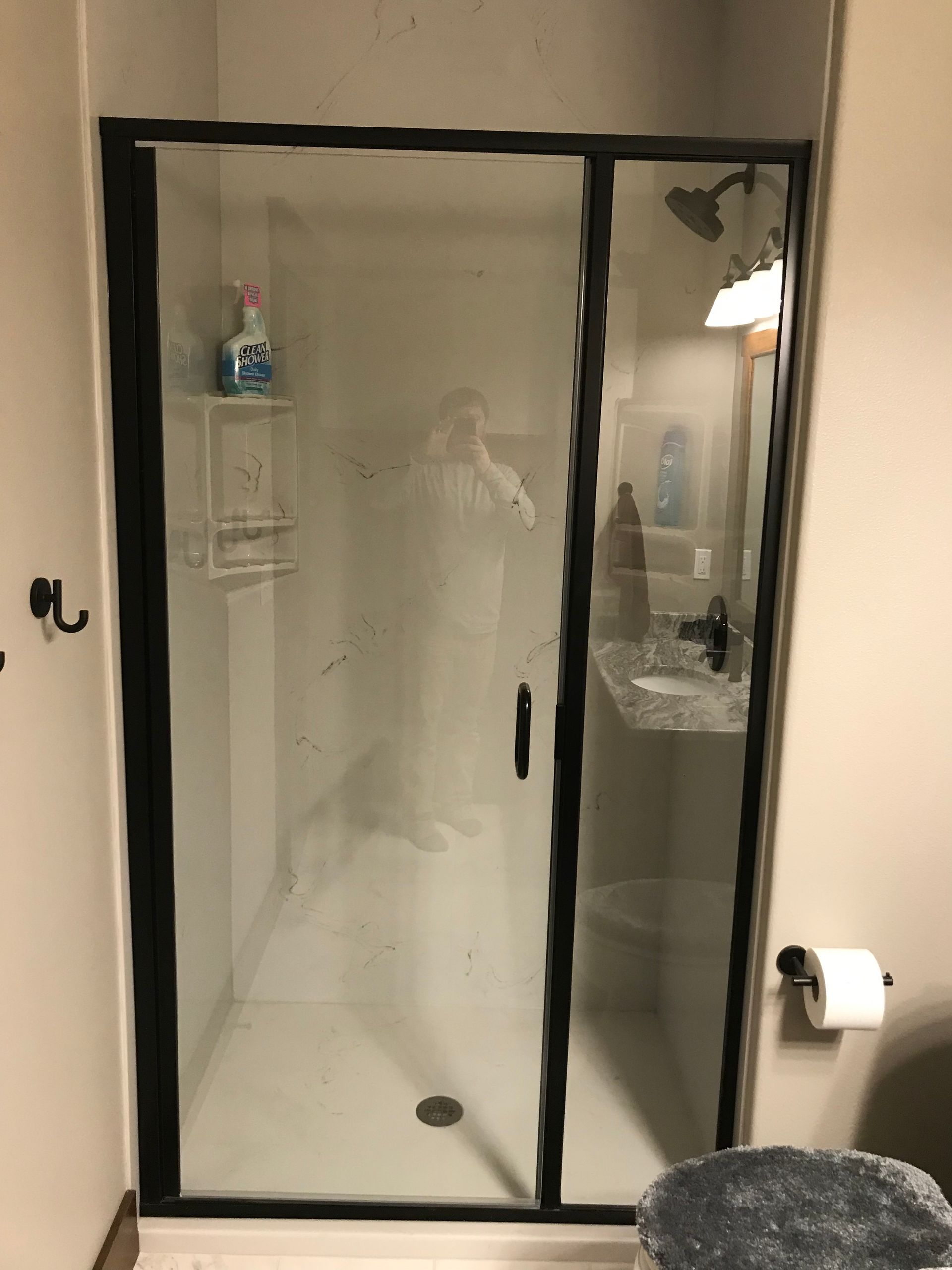 A bathroom with a black shower door and a sink.