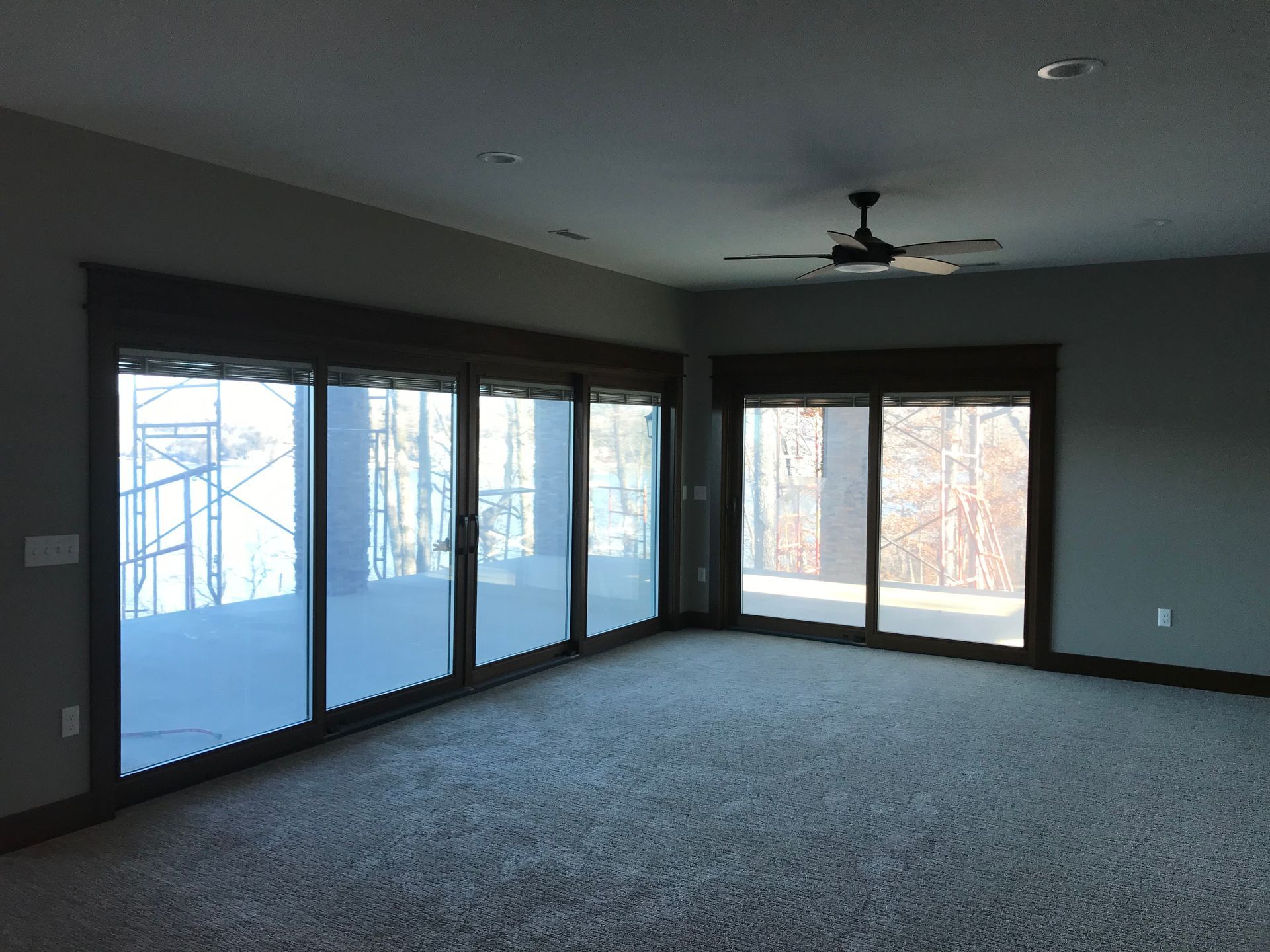 An empty room with a lot of windows and a ceiling fan