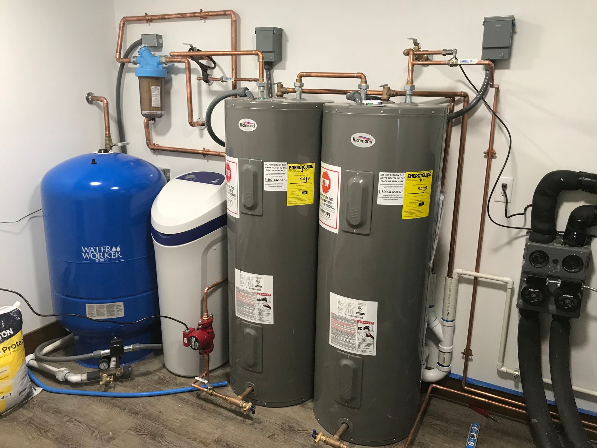 Two water heaters are sitting next to each other in a room.