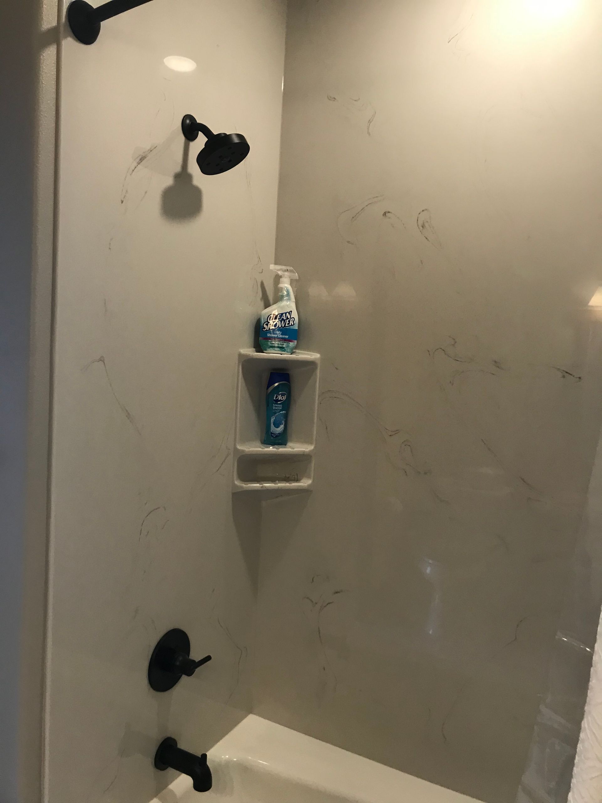 A bathroom with a tub , shower , and soap on a shelf.