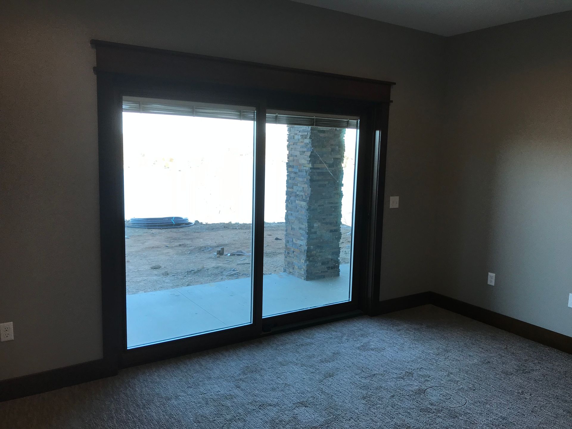 An empty room with a sliding glass door leading to a patio.