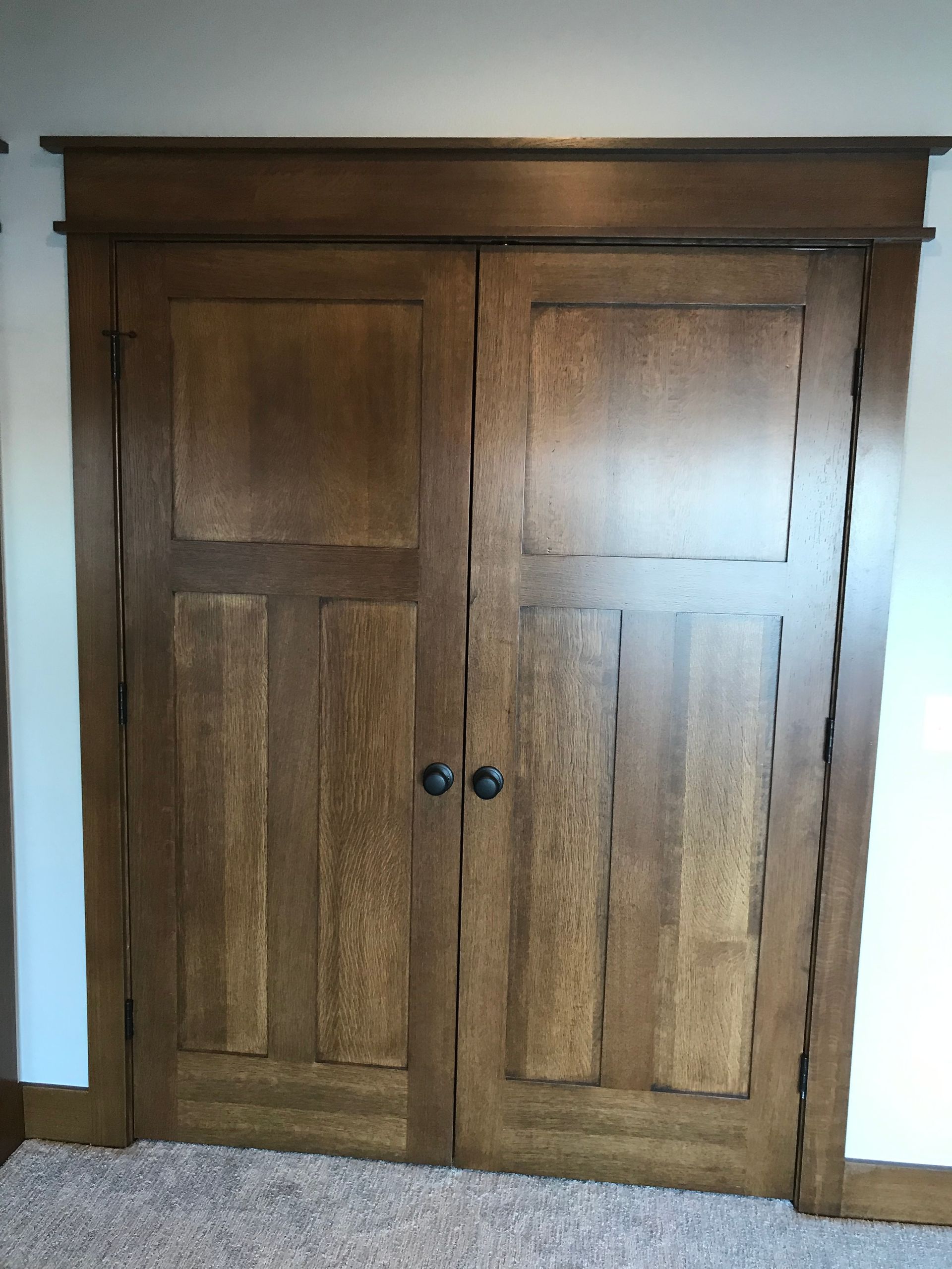 A pair of wooden doors in a room with a carpeted floor.