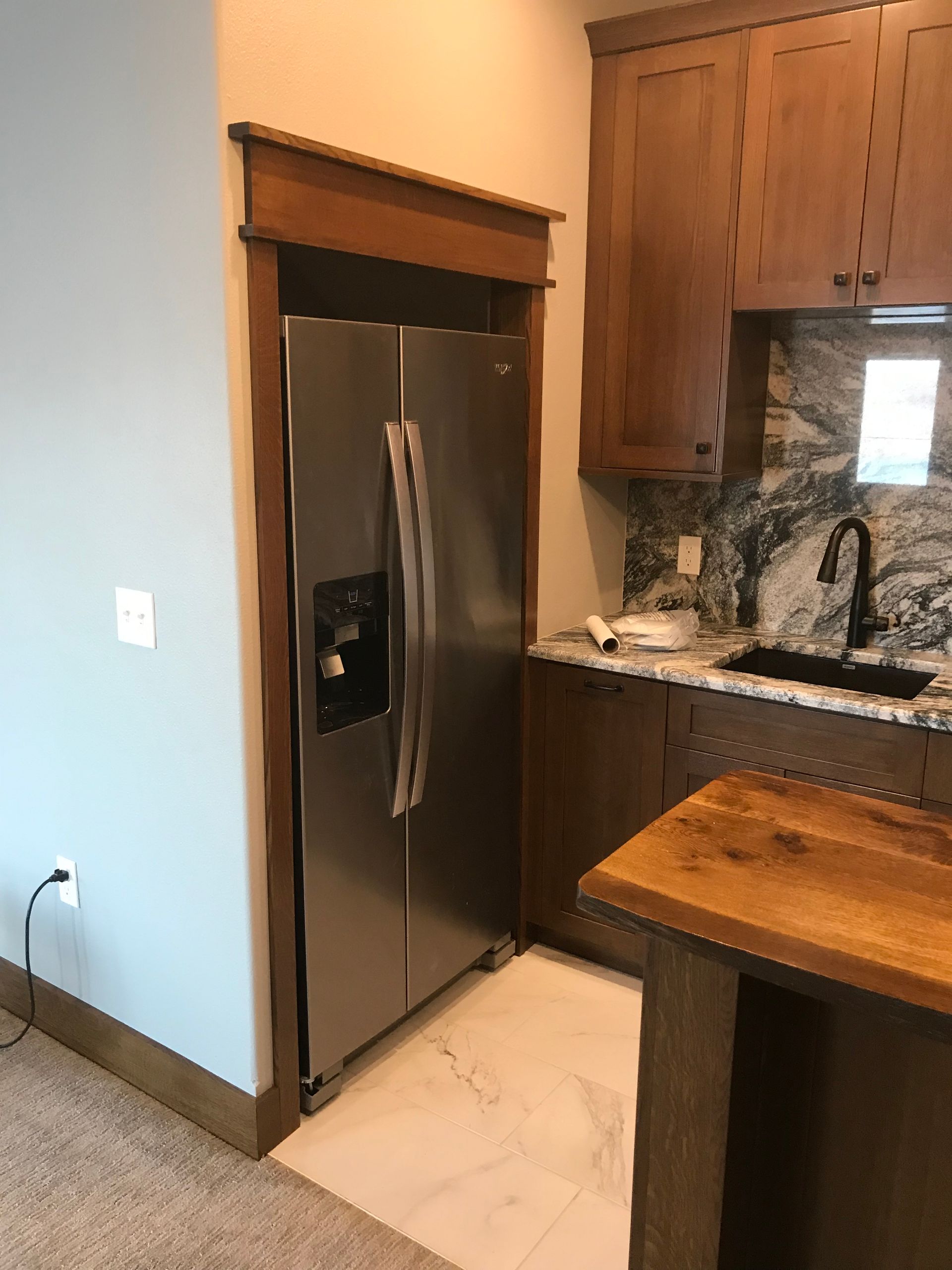 A kitchen with a stainless steel refrigerator and a wooden counter top.