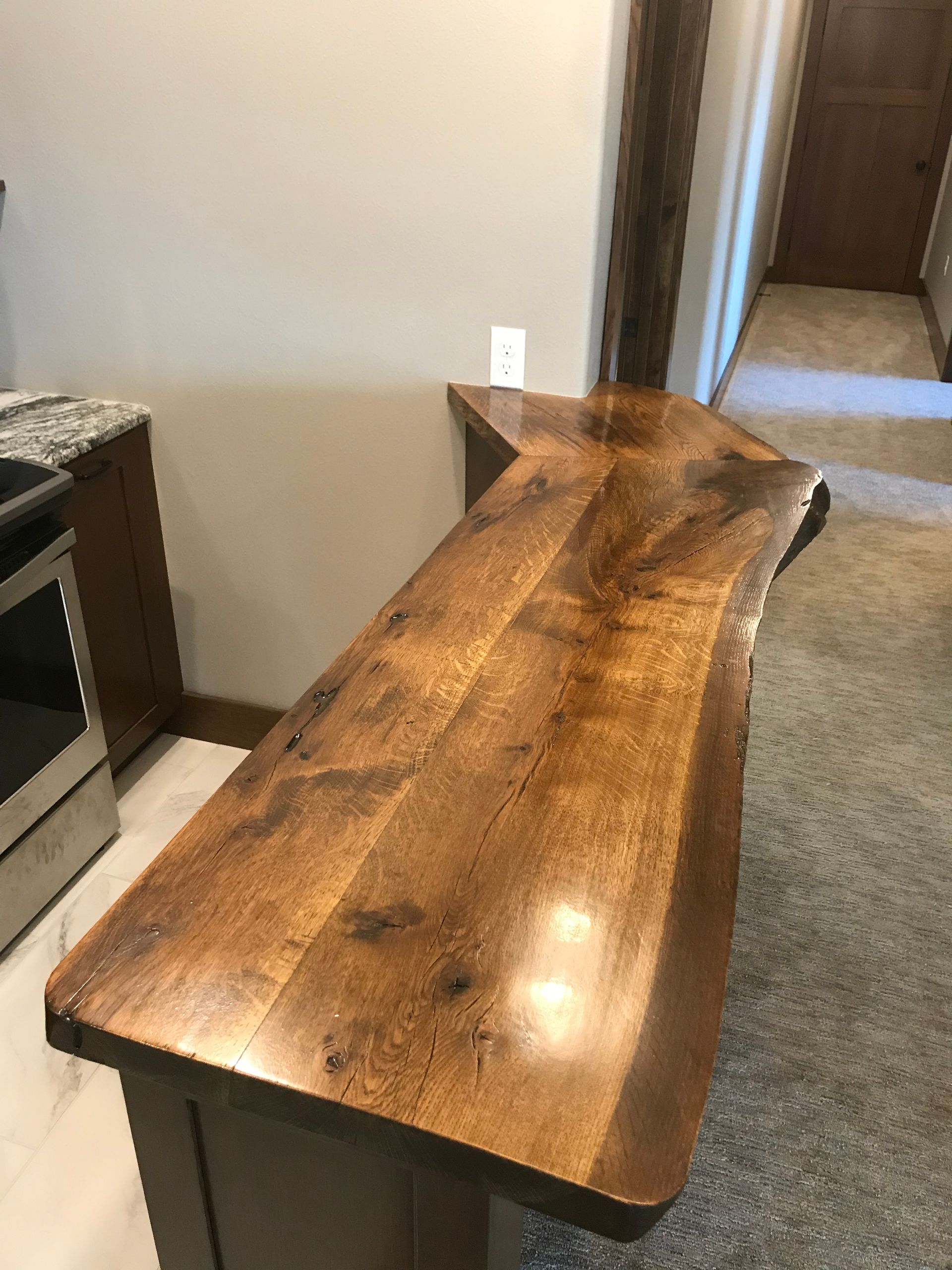 A wooden table is sitting in a kitchen next to a stove.