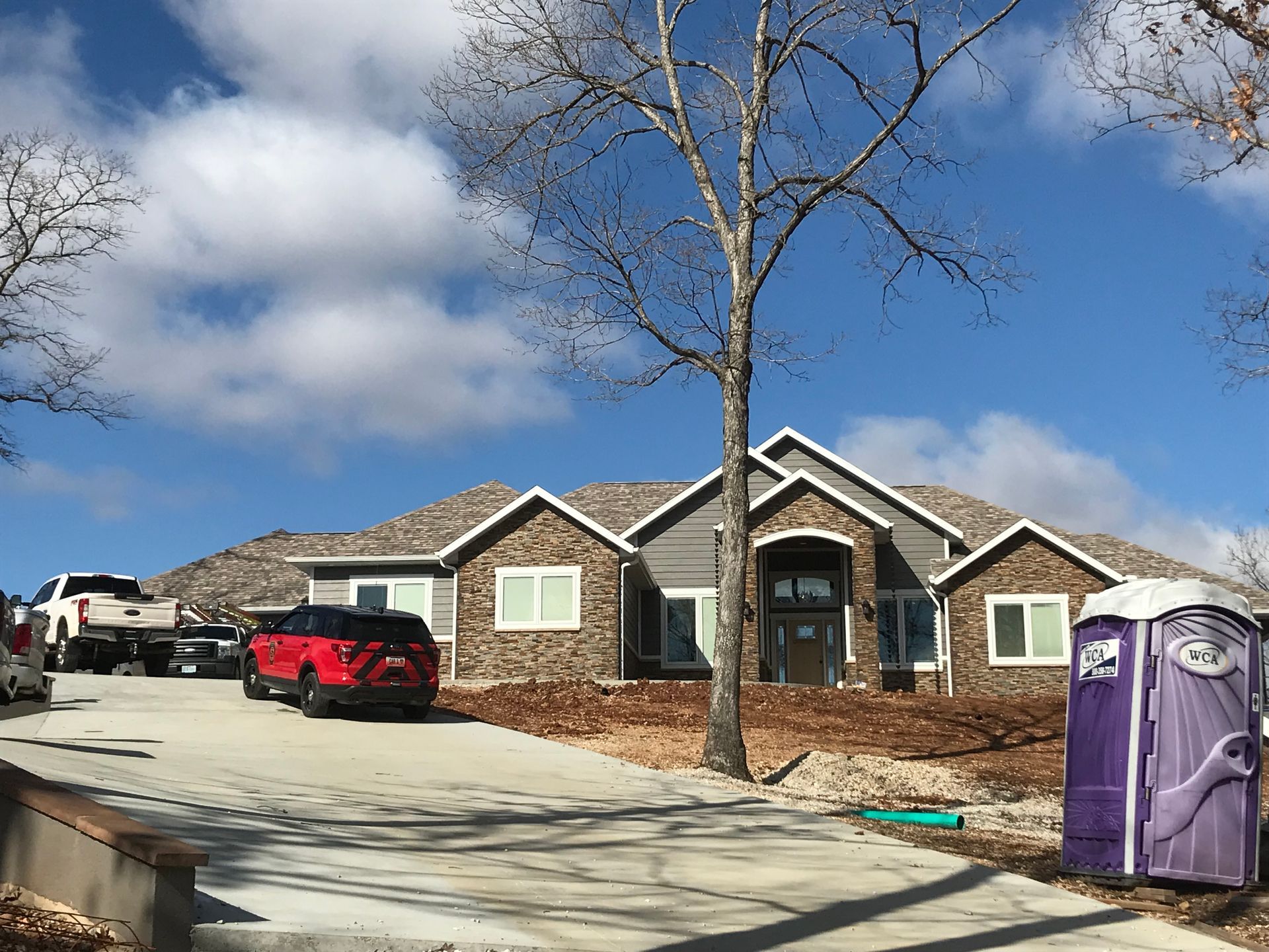 A large house with a purple portable toilet in front of it.