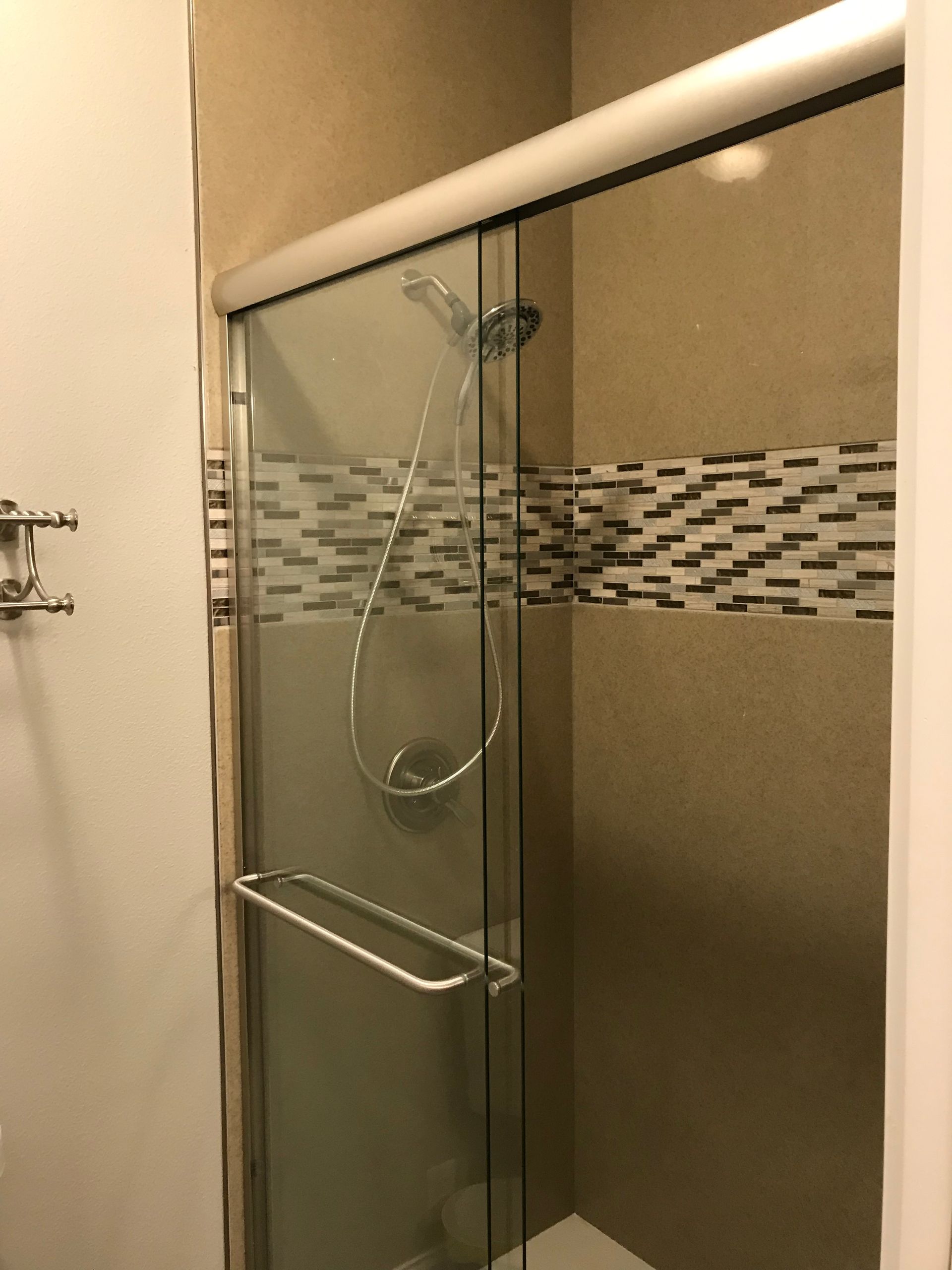 A bathroom with a sliding glass shower door and a shower head