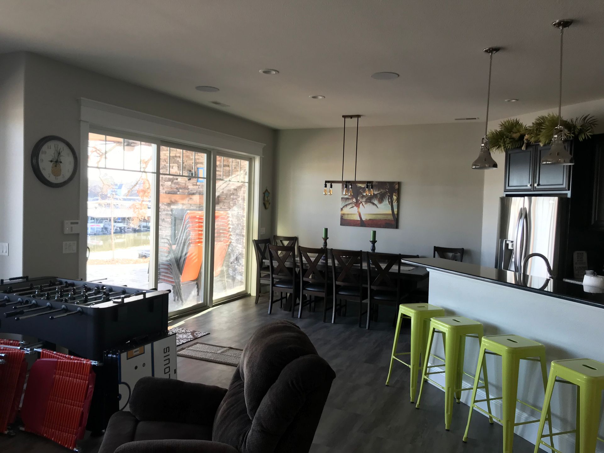 A living room with a table and chairs and a clock on the wall.