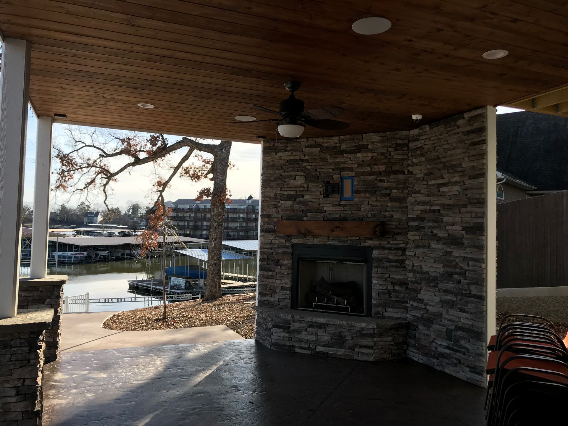 A covered patio with a fireplace and a ceiling fan.