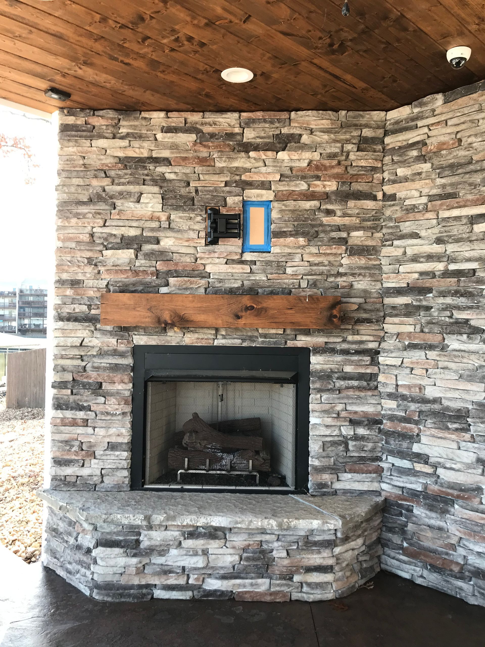 A stone fireplace with a wooden mantle and a wooden ceiling