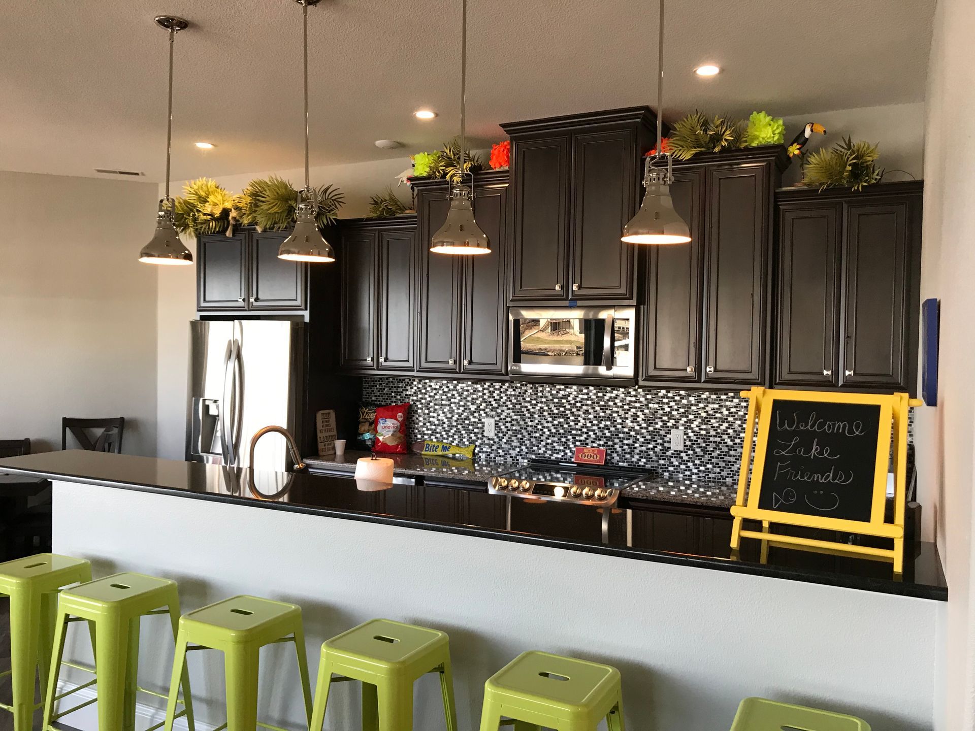 A kitchen with black cabinets and green stools