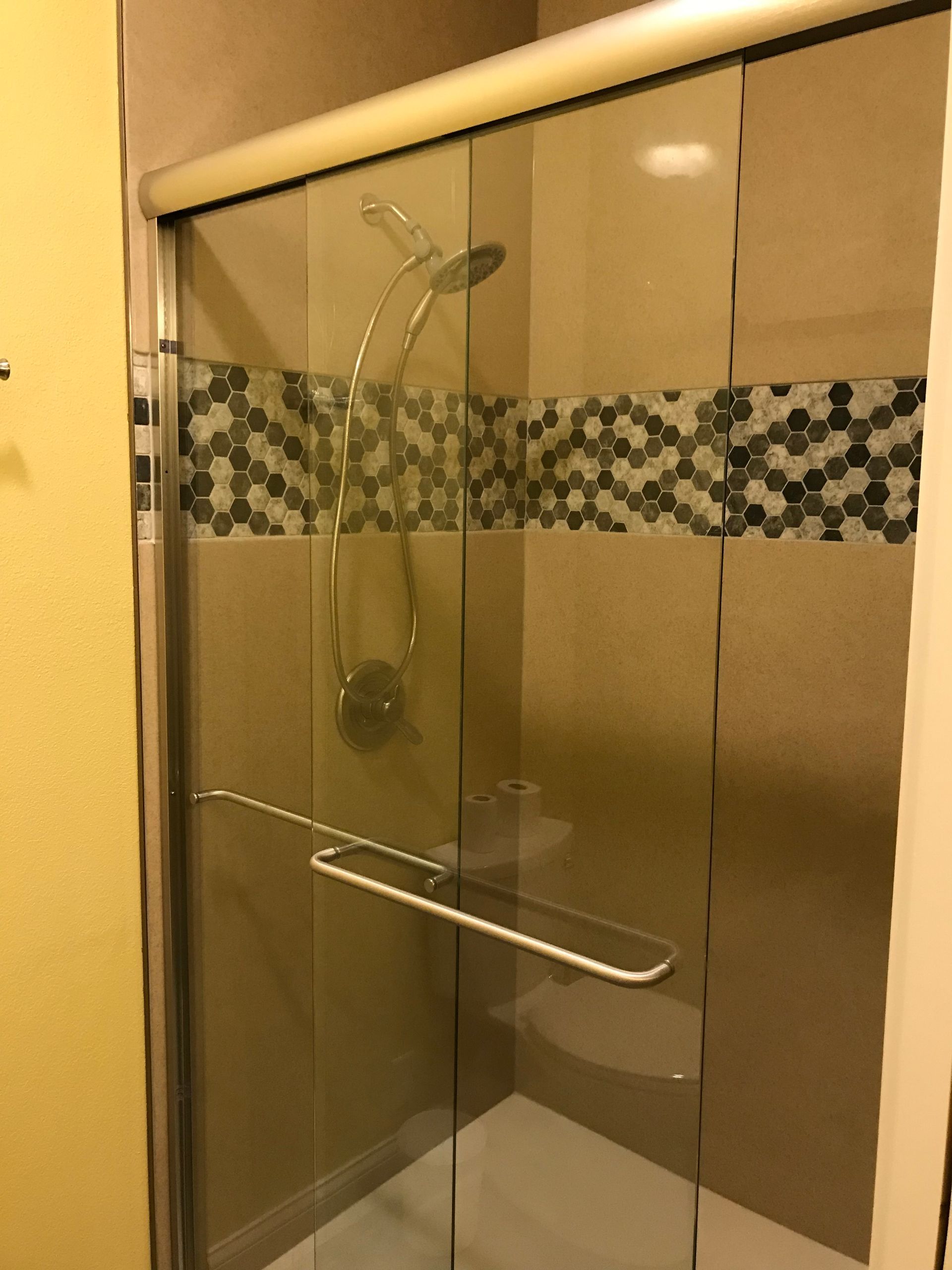 A shower with a sliding glass door and a shower head