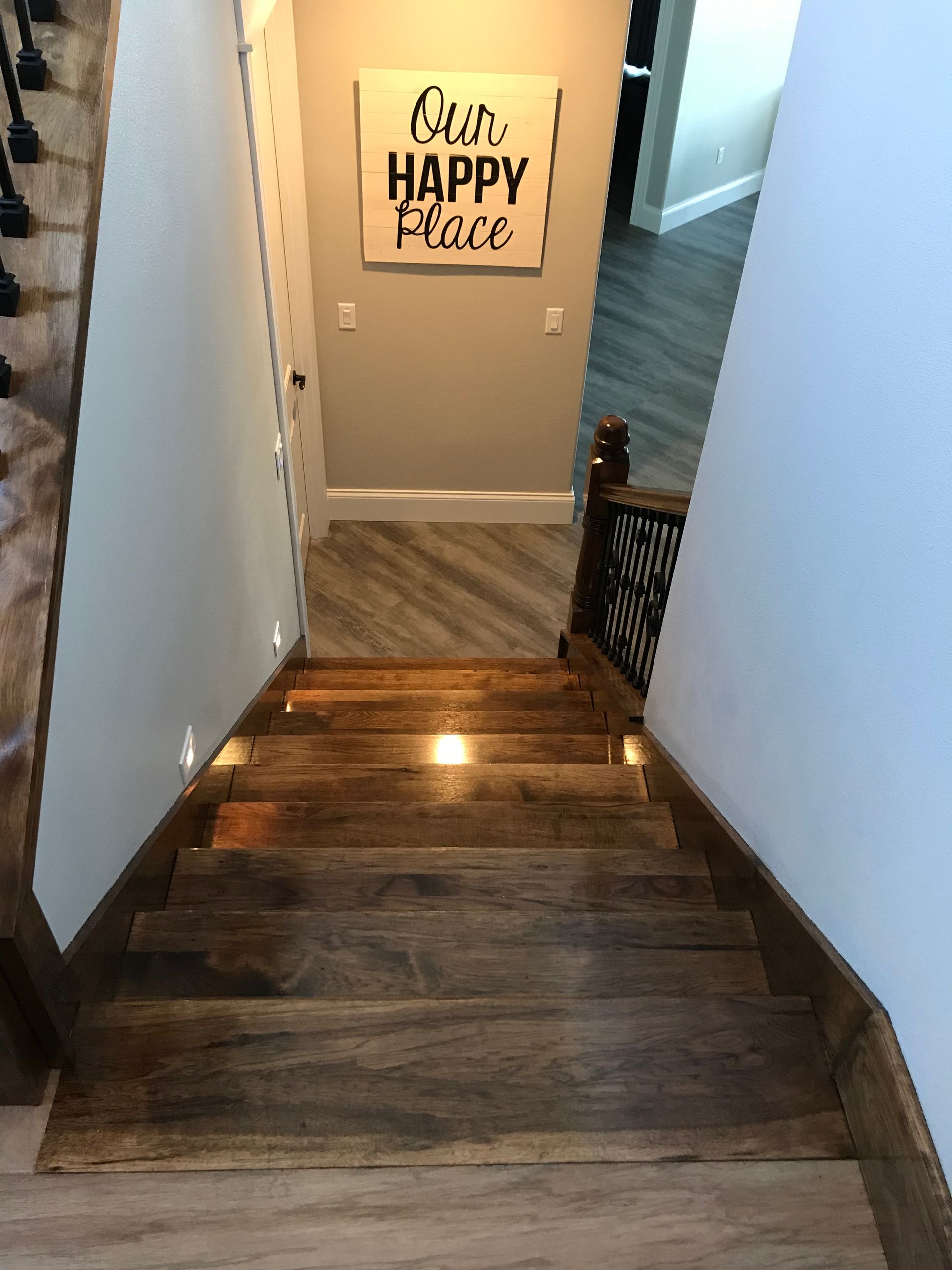 A wooden staircase with a sign on the wall that says `` our happy place ''.