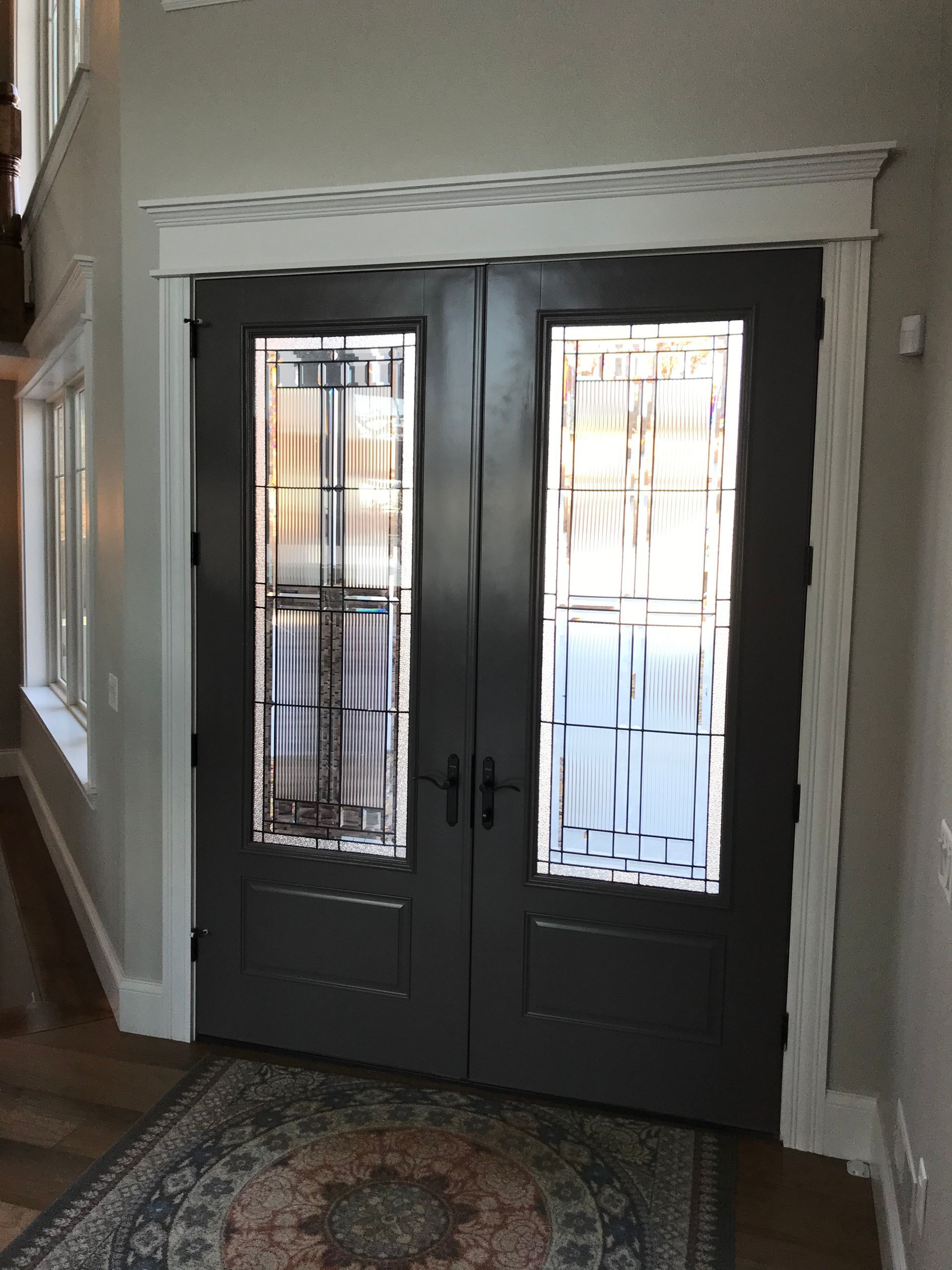 A hallway with a rug and a stained glass door
