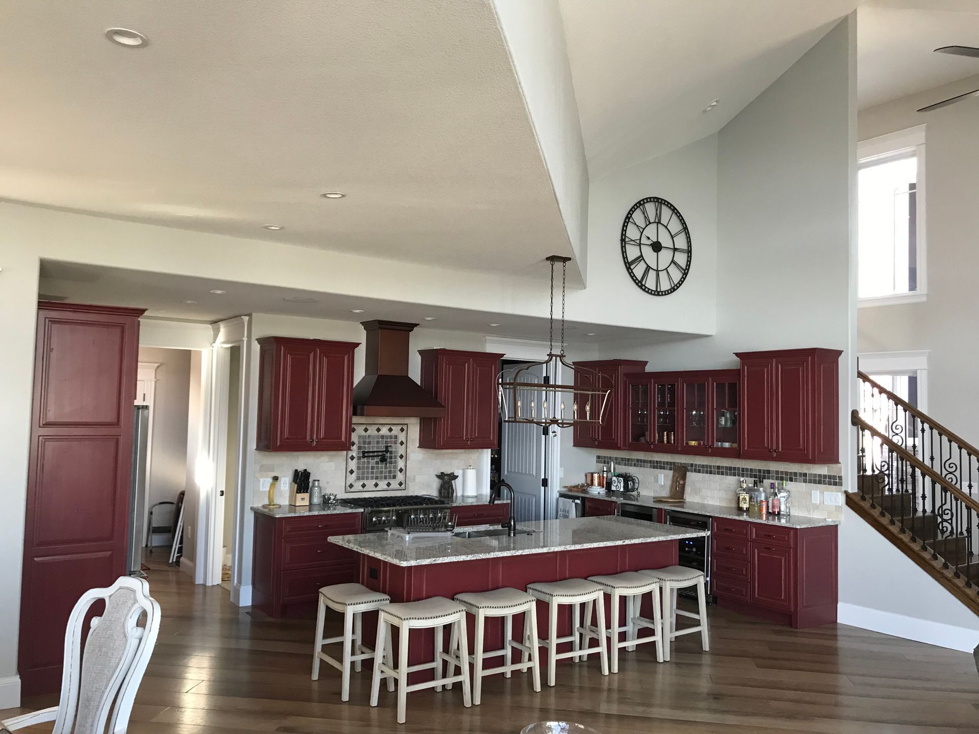 A kitchen with red cabinets and a clock on the wall