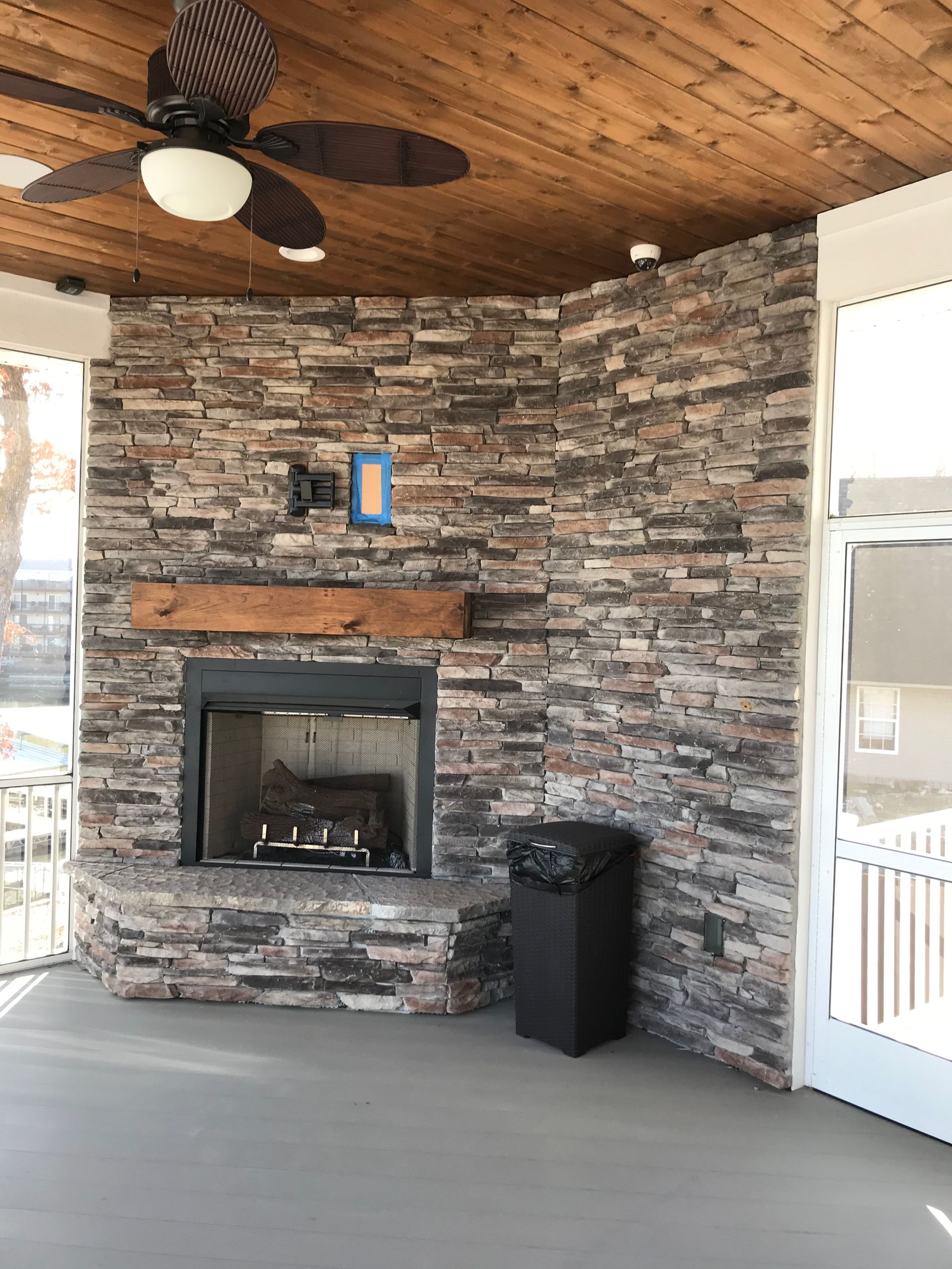 There is a fireplace in the middle of the room with a ceiling fan.