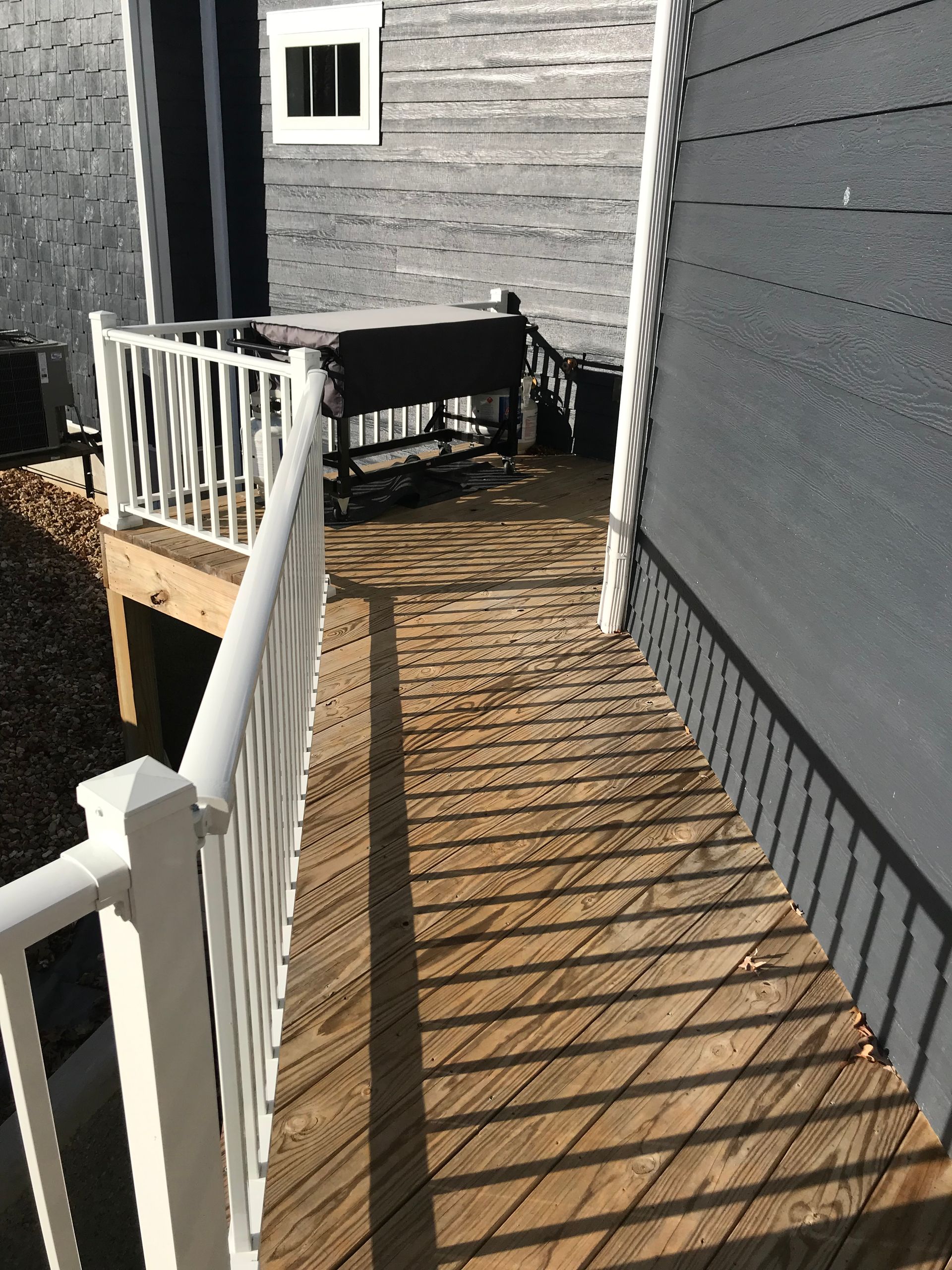 A wooden deck with a white railing next to a house