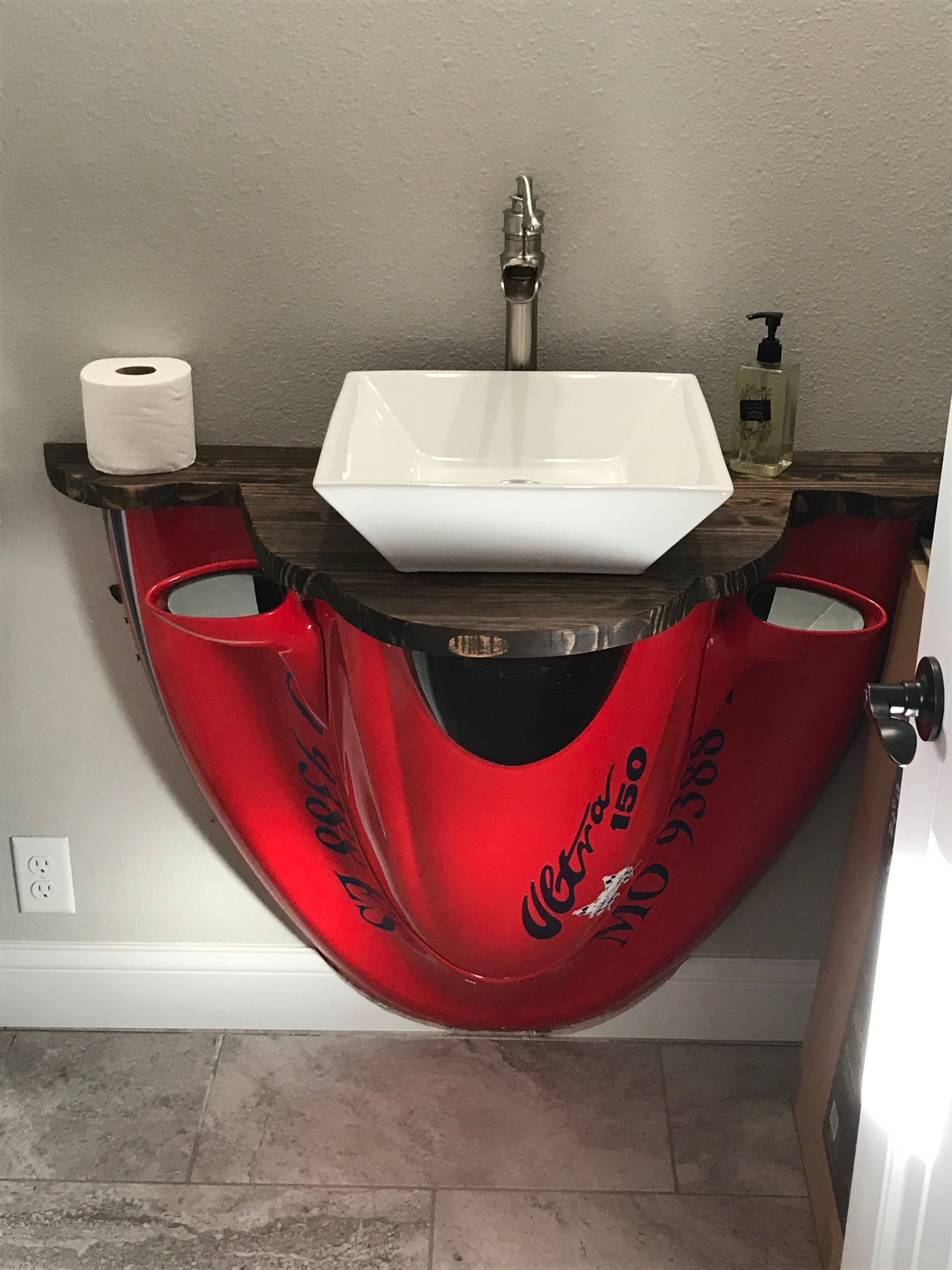 A bathroom sink made out of a red motorcycle helmet