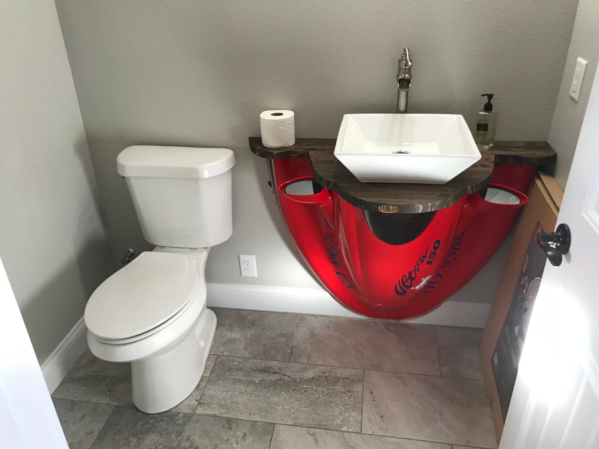 A bathroom with a toilet and a sink that looks like a jet ski.