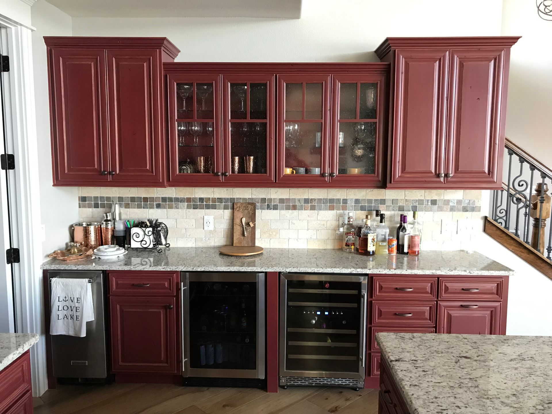 A kitchen with red cabinets and a wine cooler.