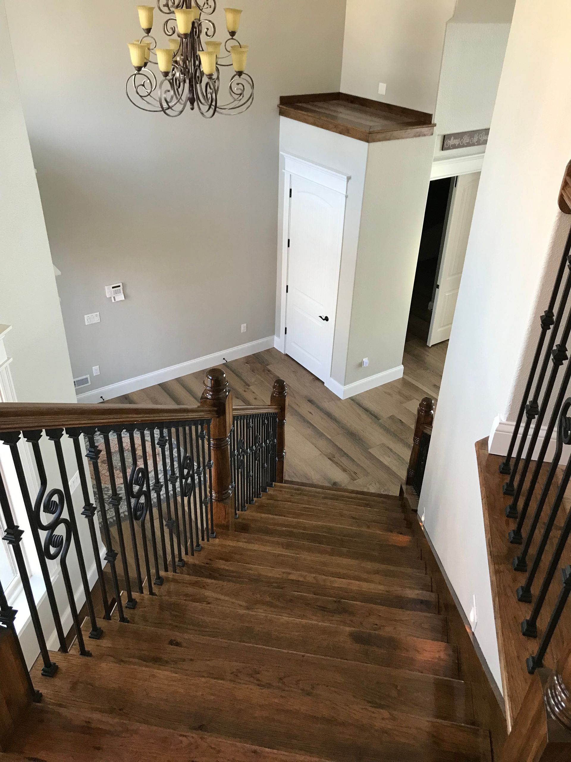 A wooden staircase with a wrought iron railing and a chandelier hanging from the ceiling.
